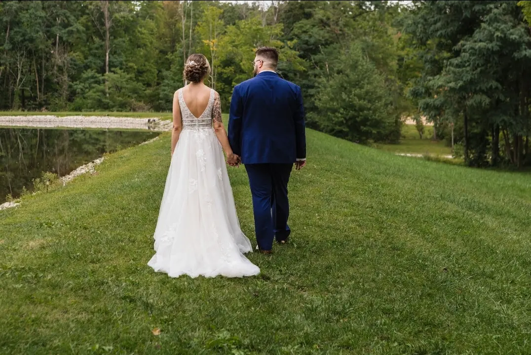 Bride wearing Boho Lace Wedding Dress called Raelynn by Rebecca Ingram walking with the groom