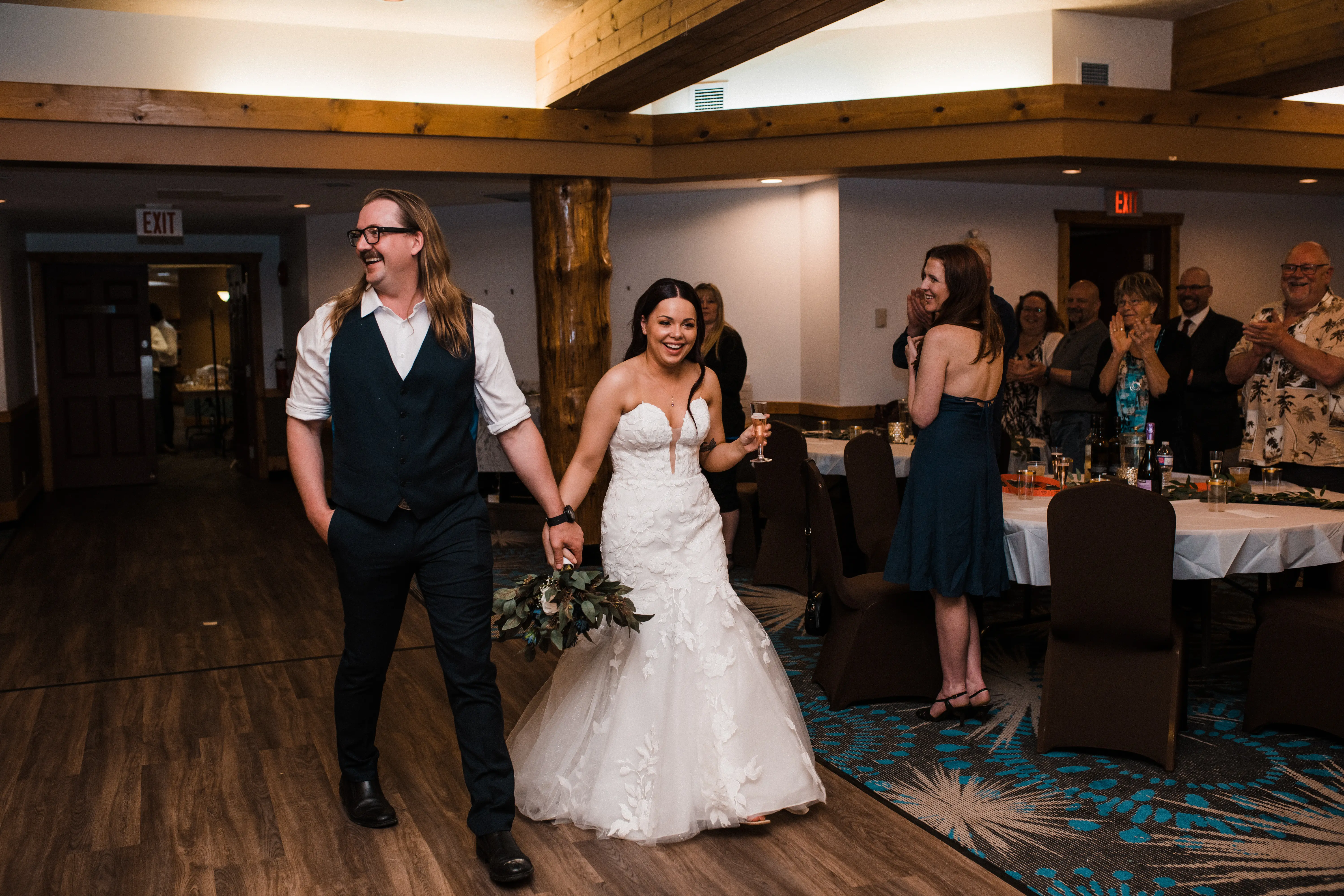 Groom Holding Hands With Bride Wearing a Floral Lace Fit-And-Flare Wedding Gown Called Hattie By Rebecca Ingram