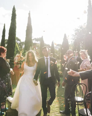 Bride in Mikado Ball Down Wedding Dress Selena by Maggie Sottero Walking Down the Isle with Groom