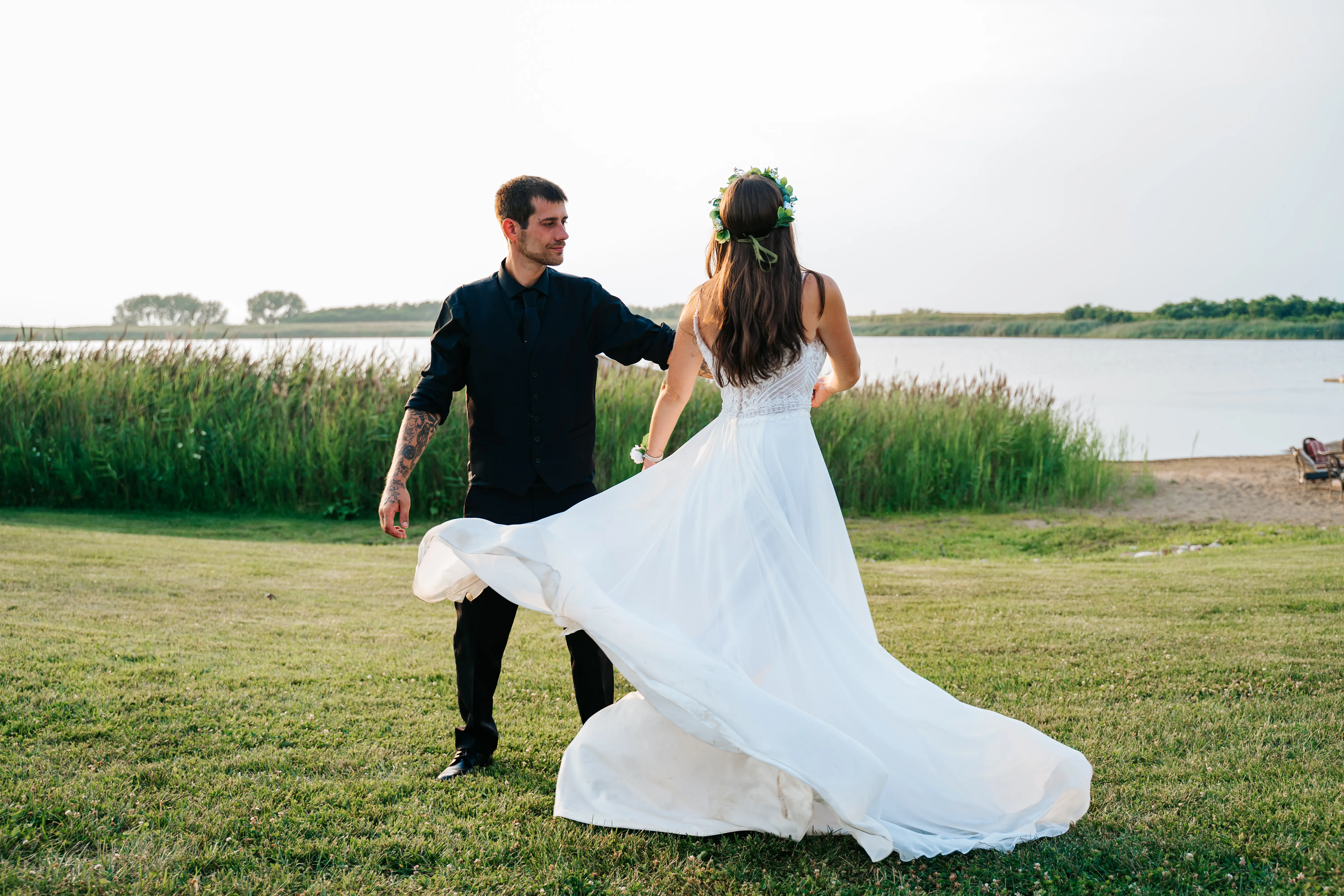 Bride Wearing Beach Sheath Wedding Dress Called Lorraine By Rebecca Ingram Dancing On A Lakefront With Groom