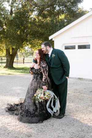 Groom hugging bride wearing black wedding dress called Zander.
