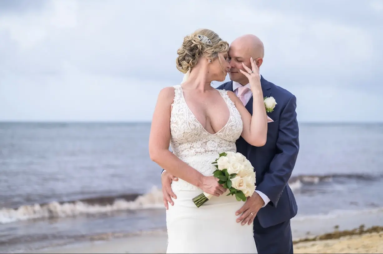Newlyweds closing eyes embracing near the shoreline.