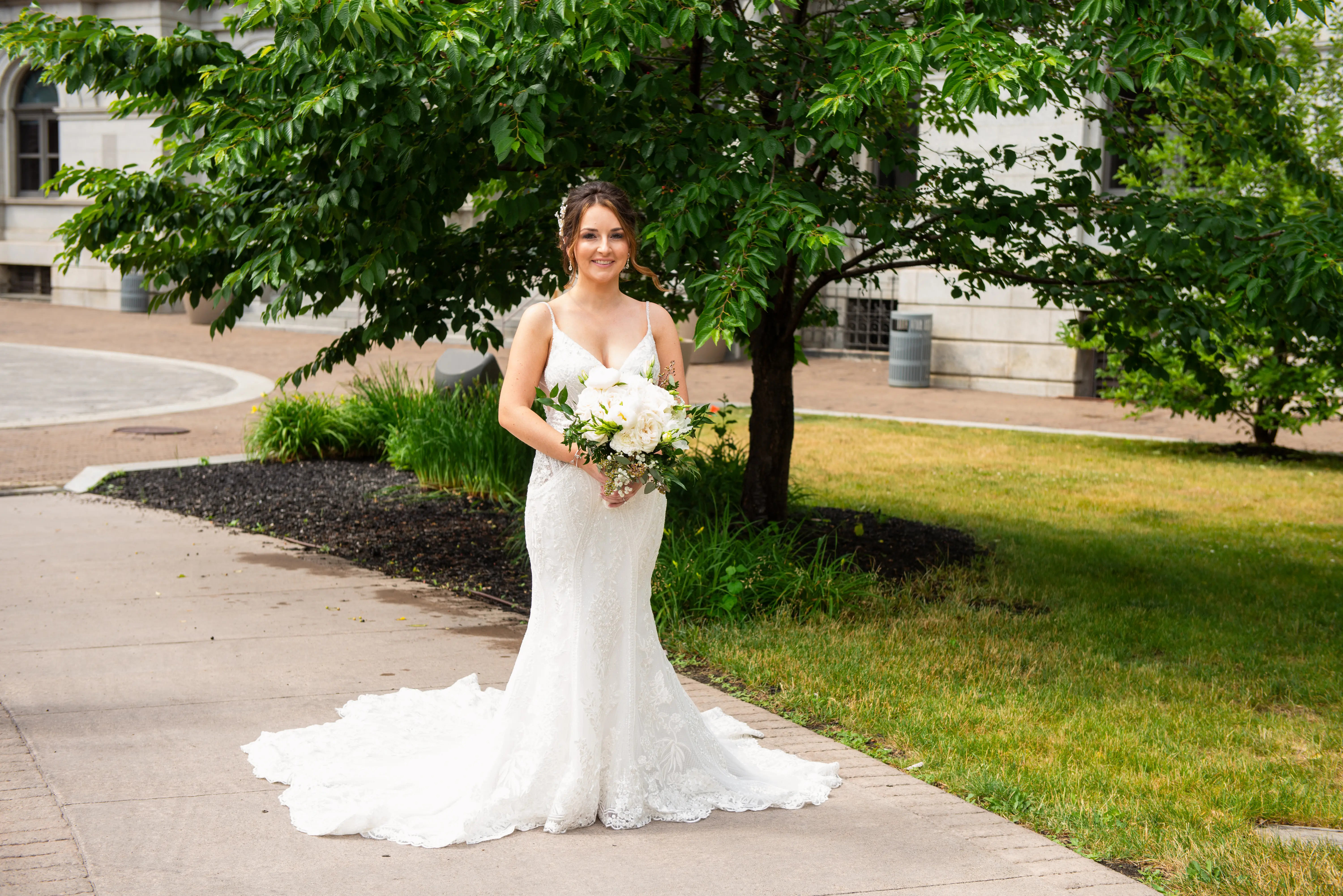 Real Bride Posing In White Wedding Dress Named Bailey By Sottero And Midgley Outside With Flowers