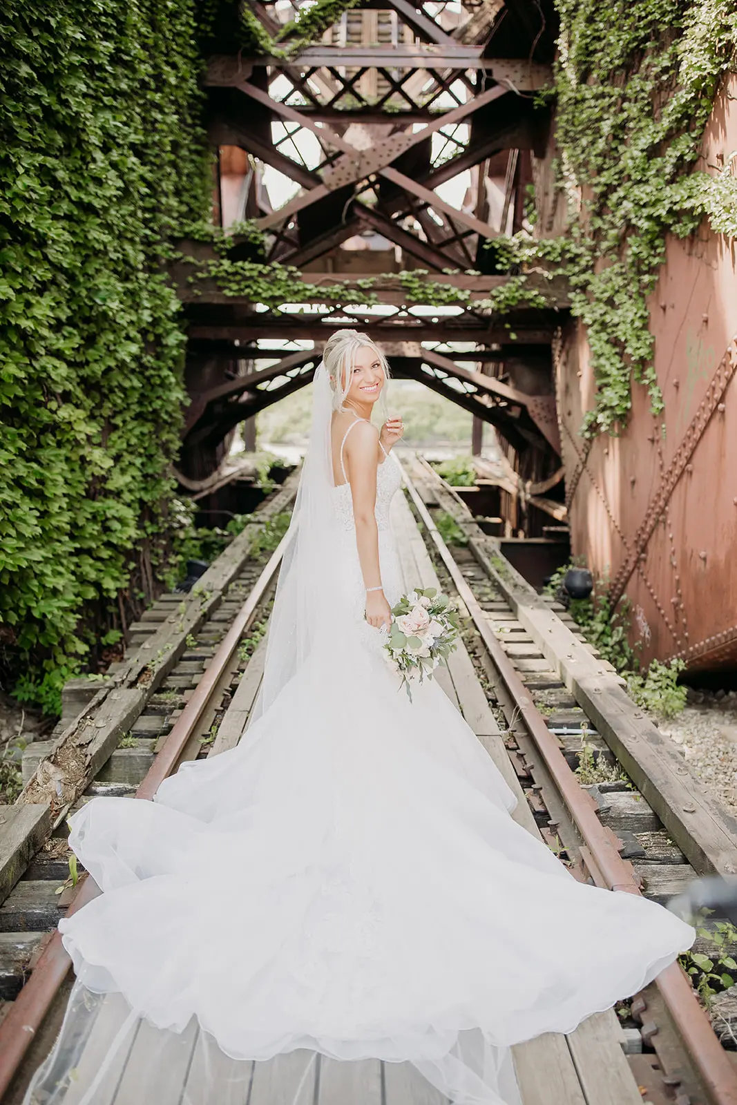 Bride stood on railway track wearing Alistaire wedding dress.