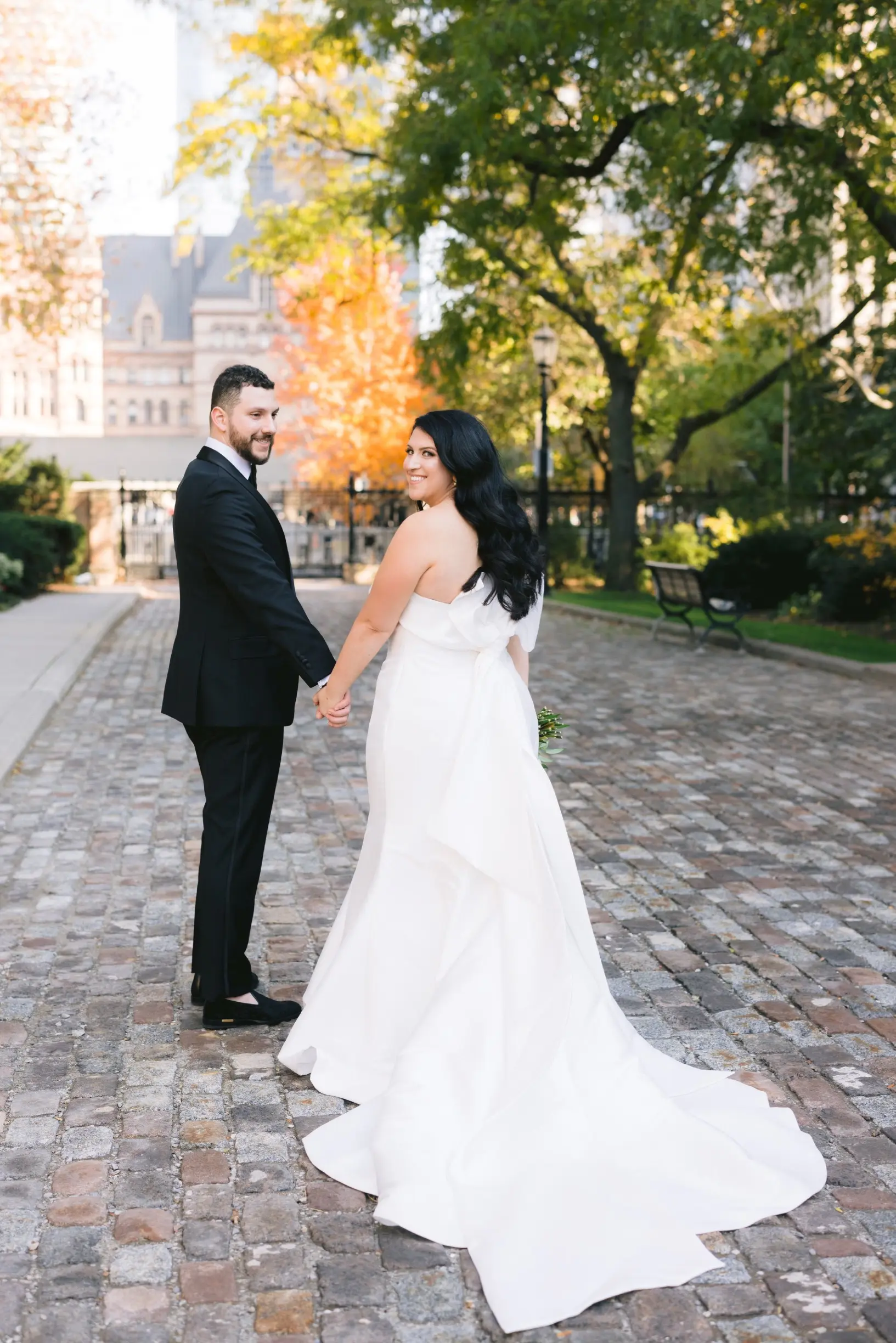 Bride with groom wearing strapless satin mermaid wedding dress with big bow on the back.