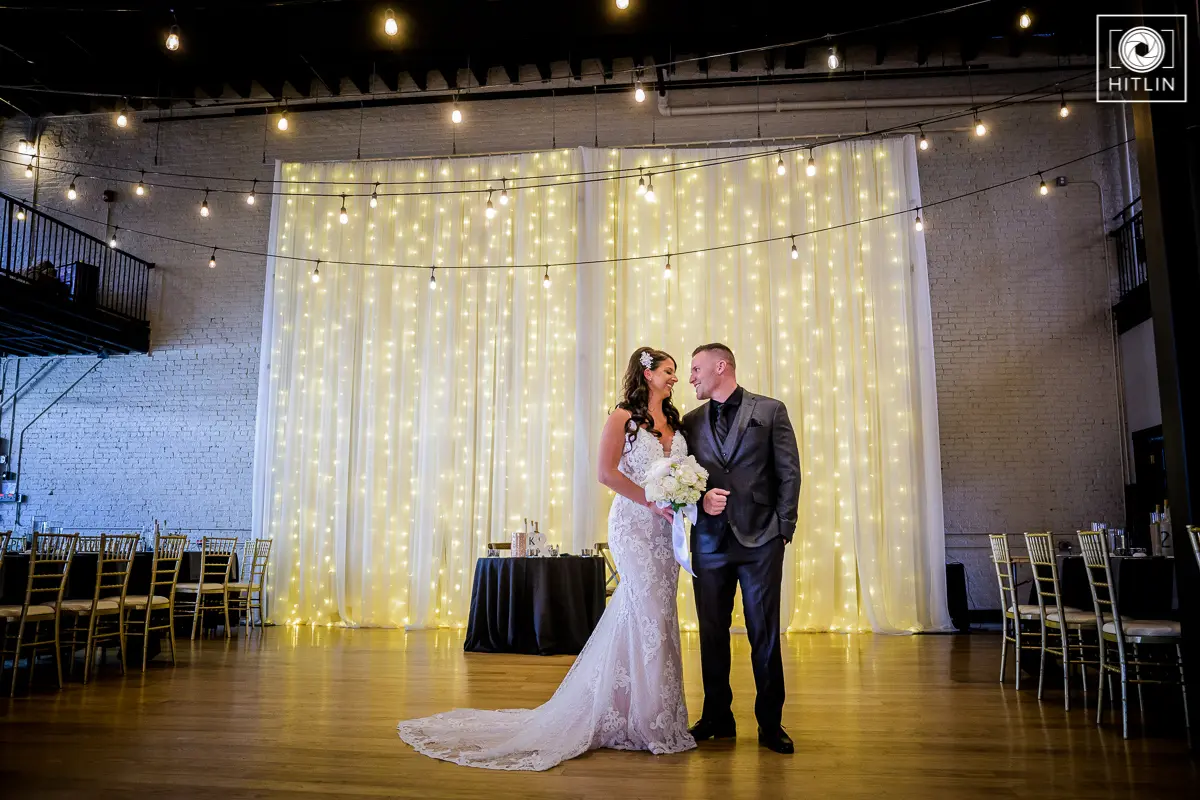 Groom at Reception Area with Real Bride in a Romantic Lace Sheath Wedding Gown with Shimmering Lace Motifs Called Tuscany Lynette by Maggie Sottero