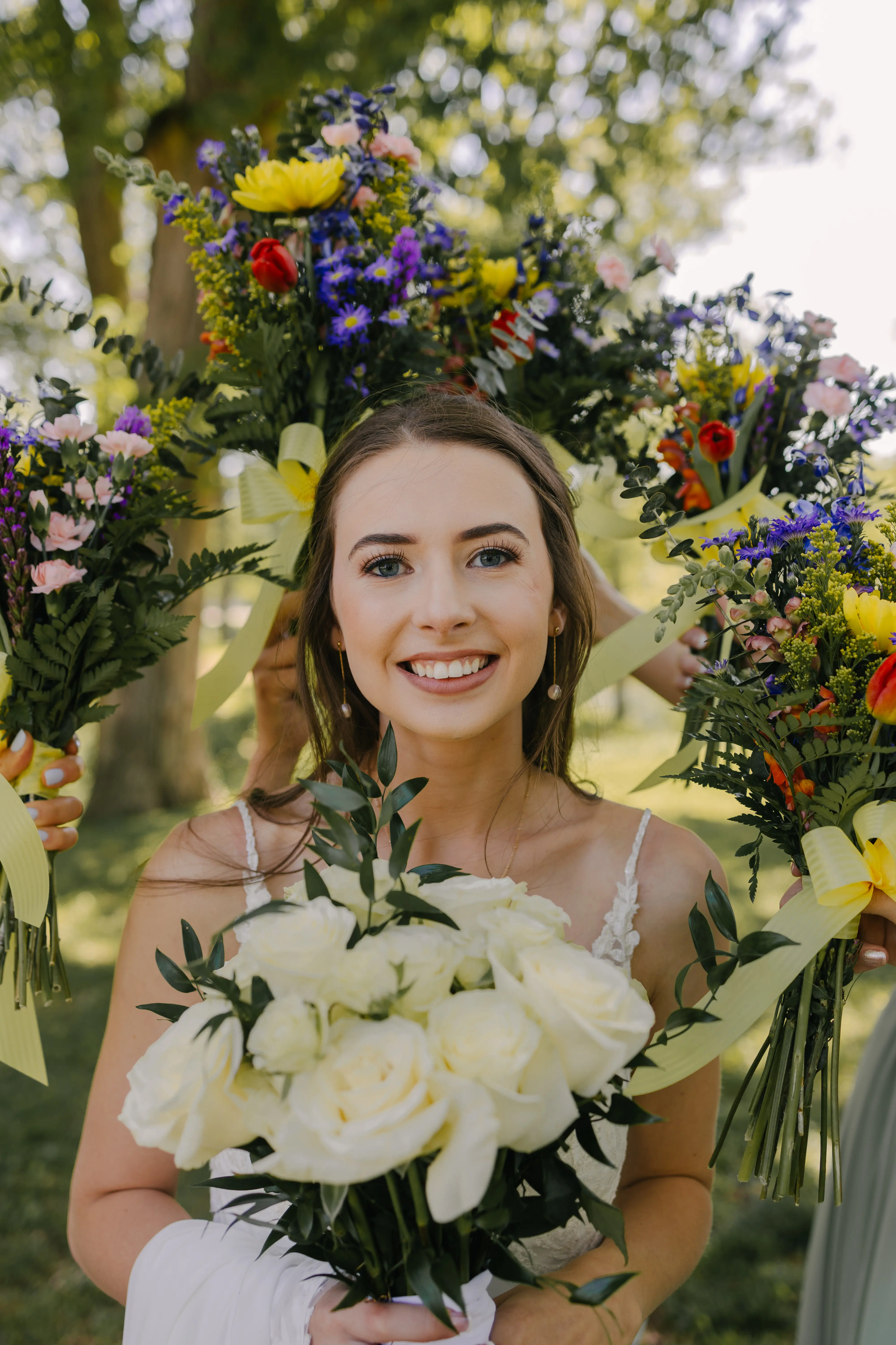 Bride wearing Charlotte by Rebecca Ingram surrounded by bridesmaid bouquets