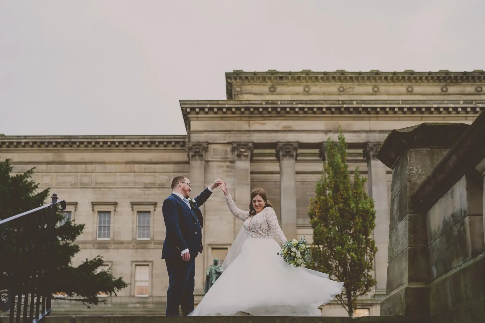 Bride Wearing Dreamy Long Sleeve Ballgown Wedding Dress Called Mallory Dawn By Maggie Sottero Twirling With Groom Outside