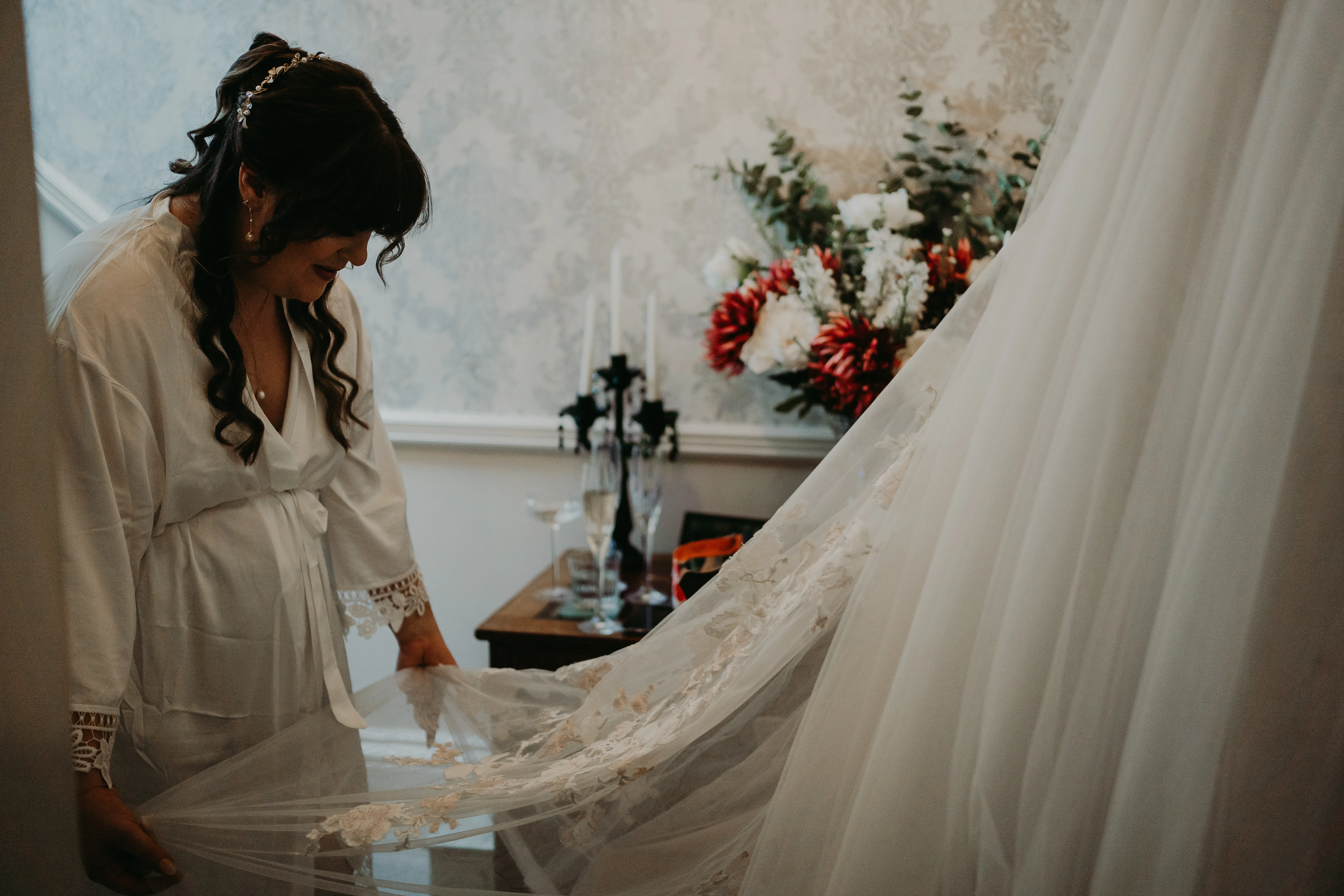 Bride admiring the lace detail of her wedding dress called Minerva.