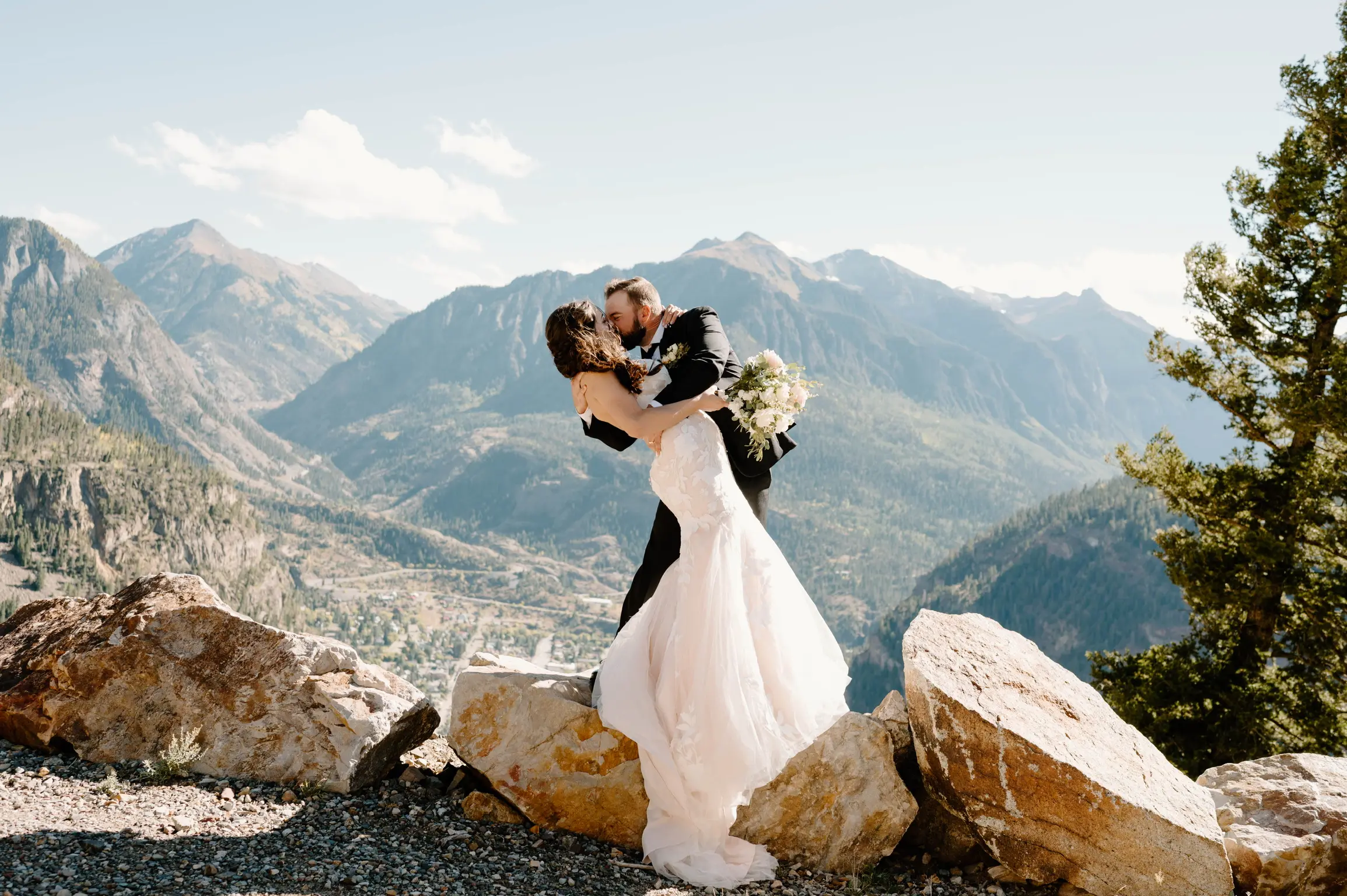 Bride wearing Hattie wedding dress by Rebecca Ingram kissing her husband on a mountian