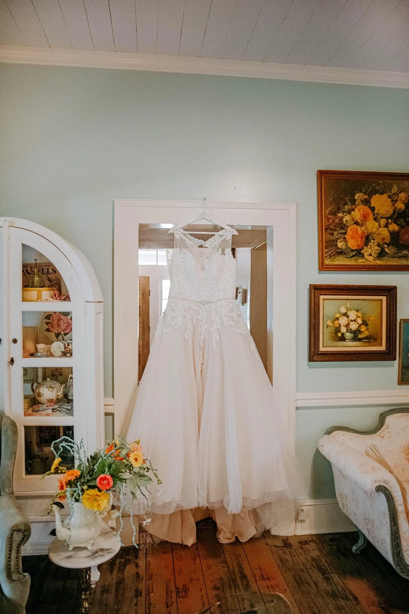 Lace Ballgown Wedding Dress Called Olivia by Rebecca Ingram Hanging on a Doorframe