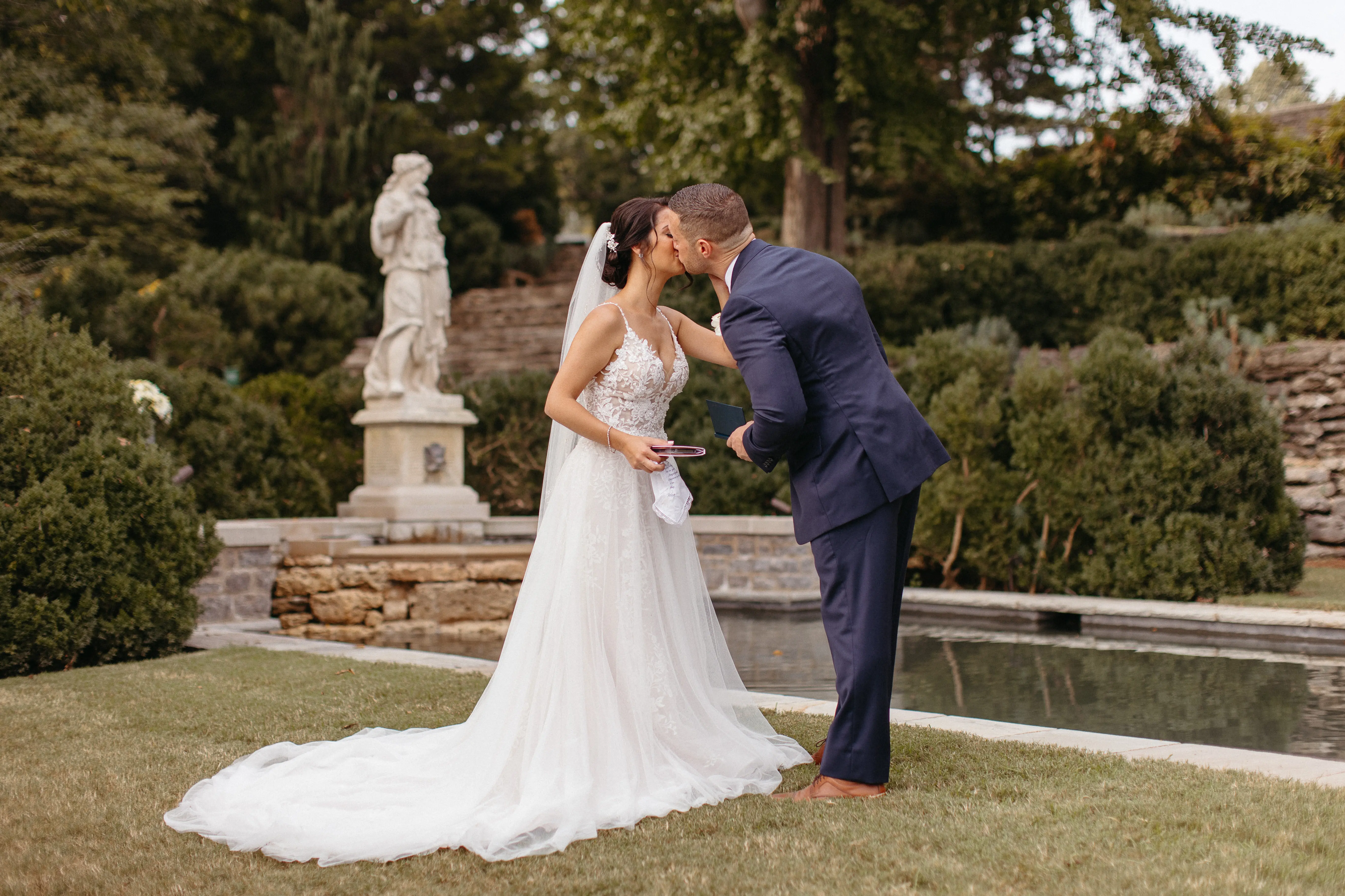 Newlyweds kissing by a historic fountain.
