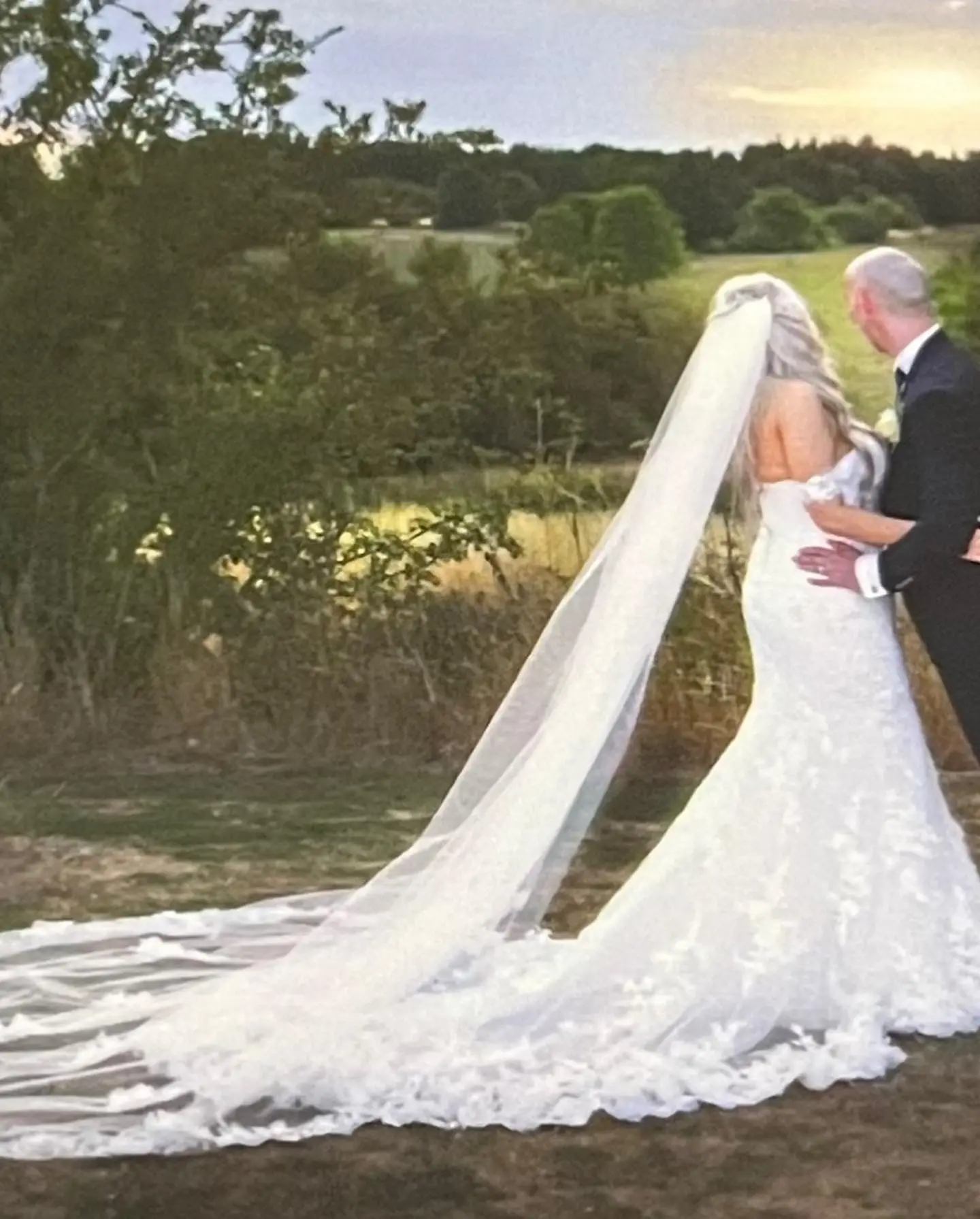 Bride and Groom Standing Together. Bride Wearing 3D Floral Lace Wedding Dress Called Ryker By Sottero And Midgley