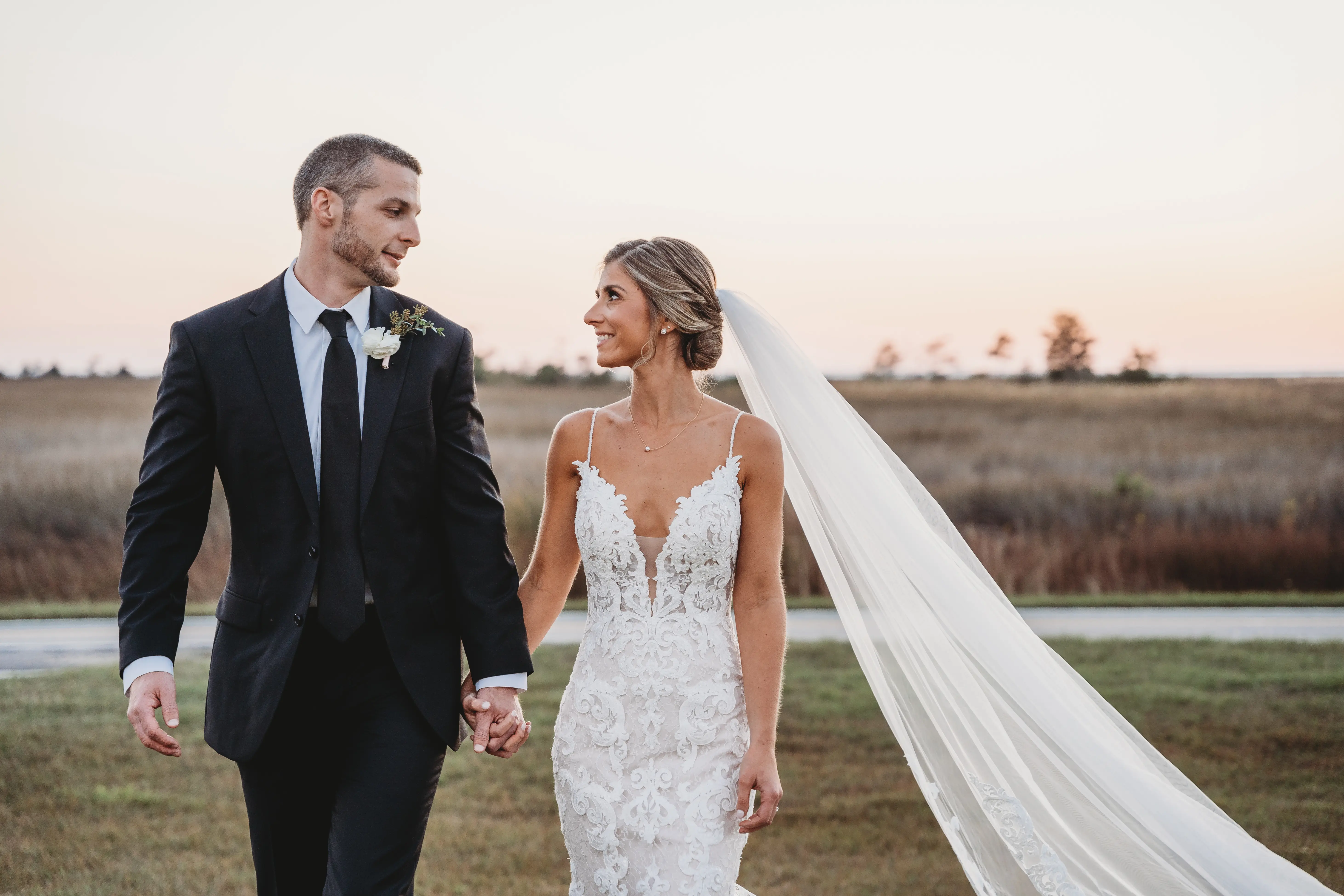 Groom Holding Hands with Bride in Mermaid Wedding Dress with Shimmering Lace Motifs and Illusion Plunging Sweetheart Neckline Called Tuscany by Maggie Sottero