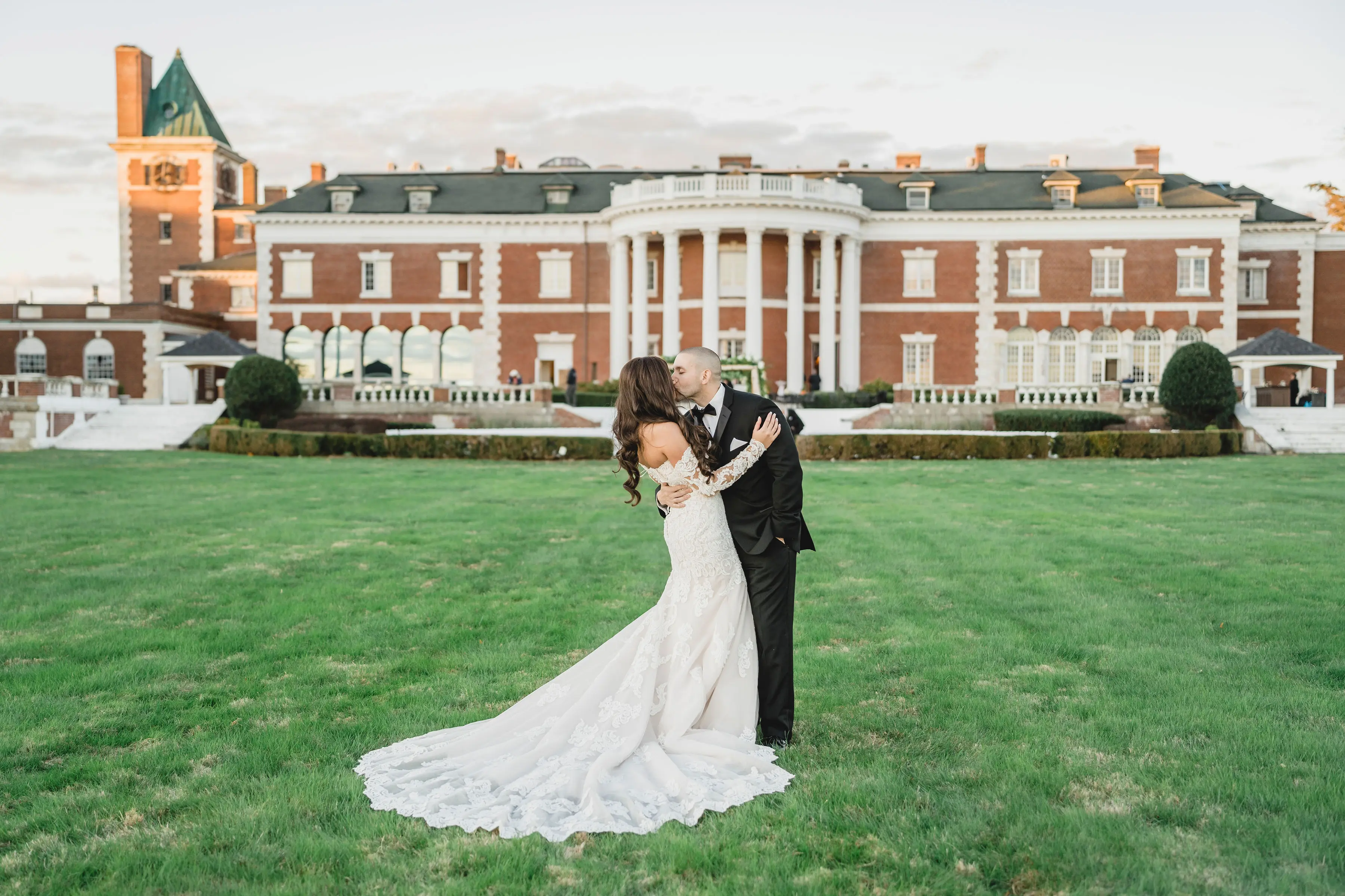 Bride Wearing Sparkly Lace Fit-and-Flare Wedding Dress Kissing Groom Outdoors.
