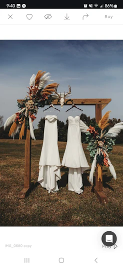 Two Maggie Sottero Wedding Dresses Hanging From A Decorated Post