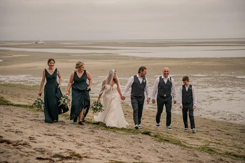 Bride wearing Boho Wedding Dress called Stevie by Maggie Sottero on the beach with her groom and bridal party