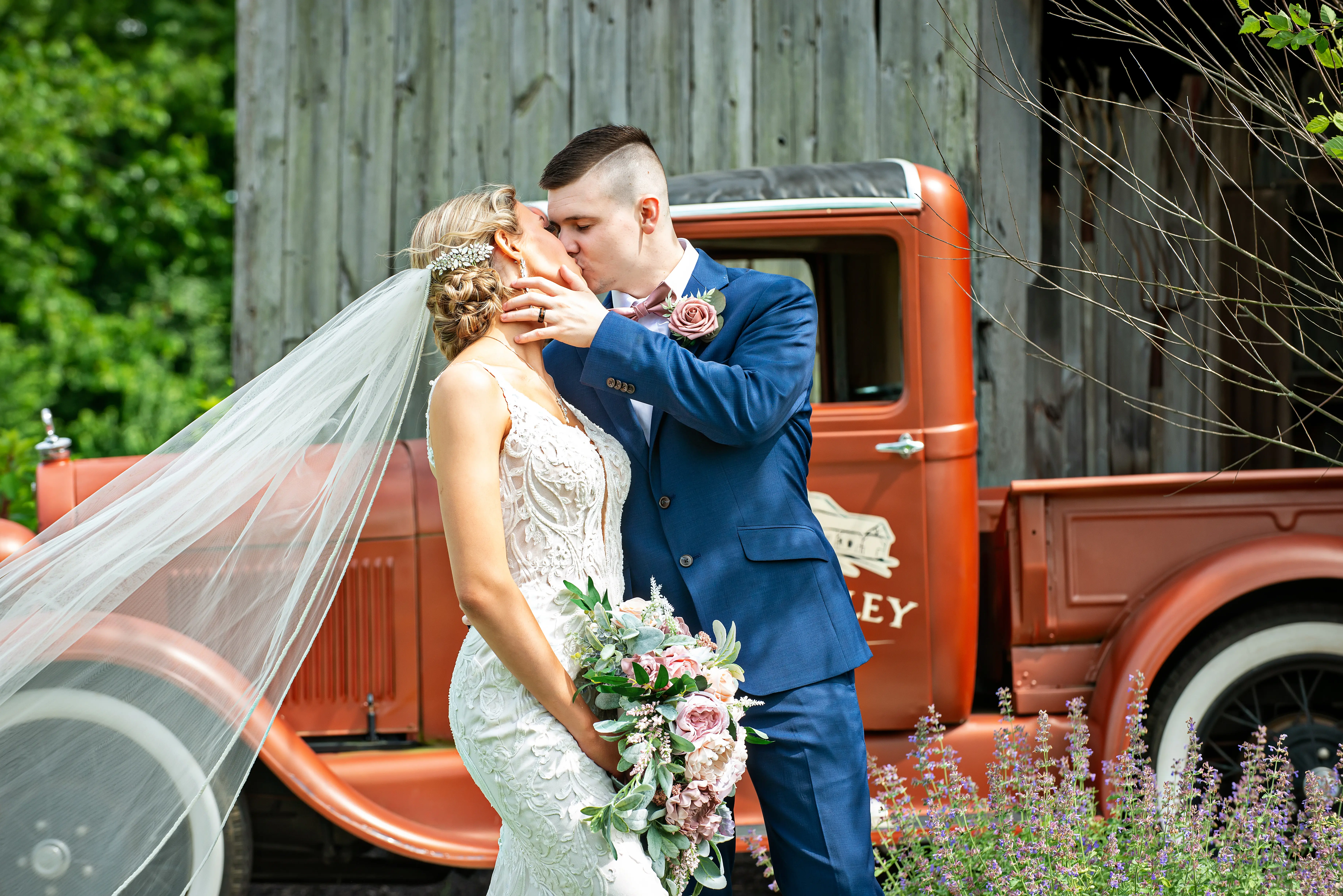 Groom Kissing Bride in Elegant Lace Sheath Wedding Dress with Beaded Lace Motifs over Textured Tulle Called Hamilton by Sottero & Midgley