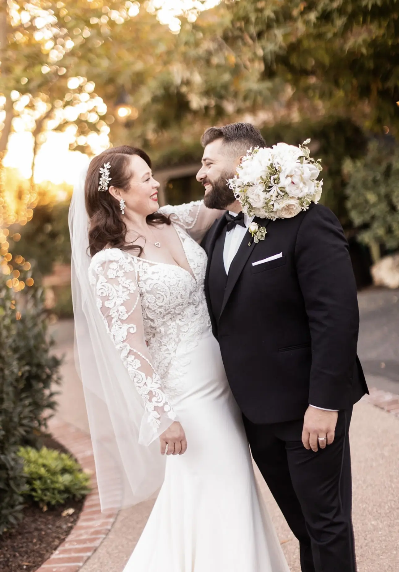 Groom Posing With Real Bride In A White Long Sleeve Wedding Dress Named Nikki By Maggie Sottero