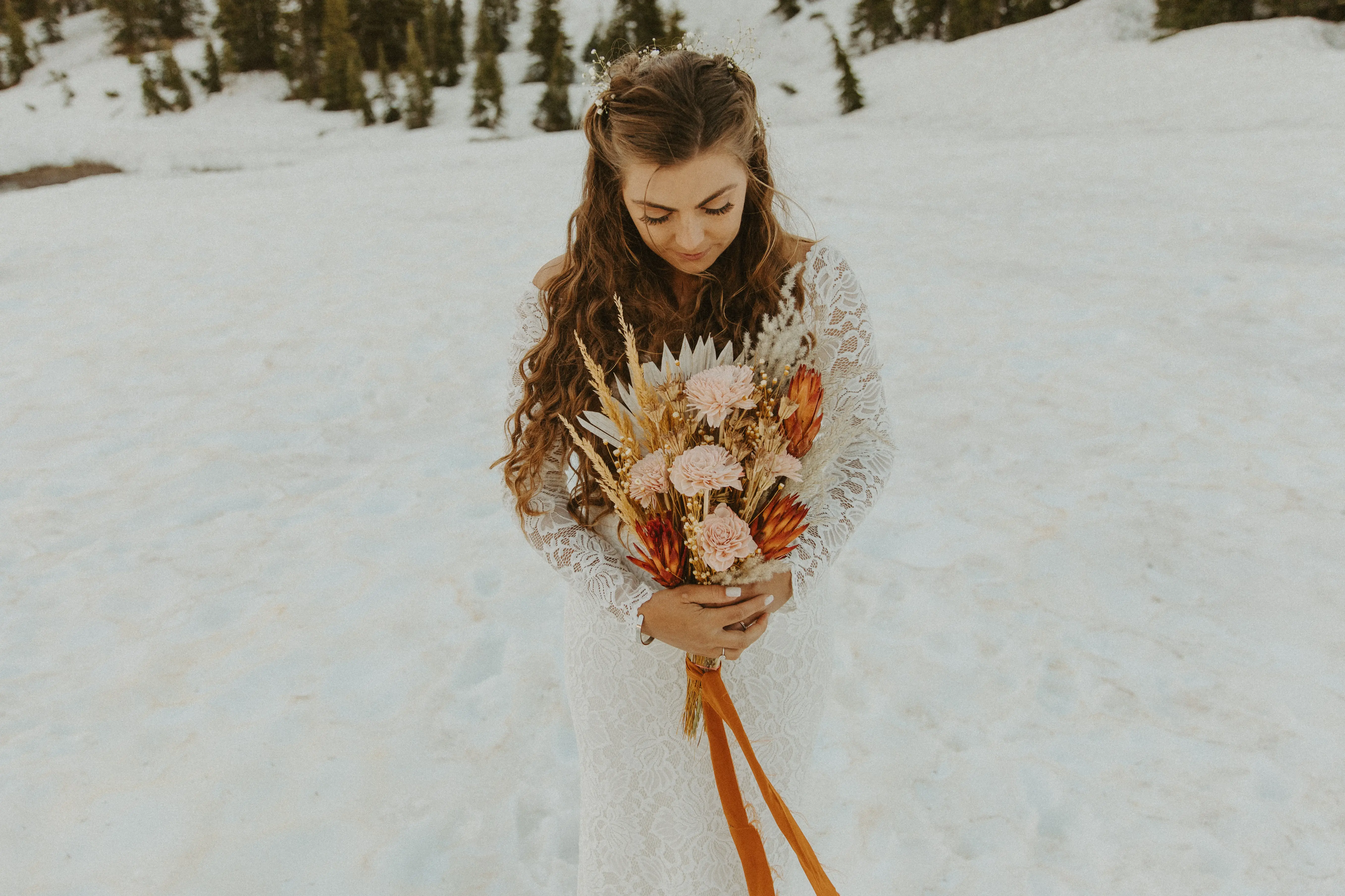 Bride holding Fall color bouquet with orange ribbon wearing long sleeved lacy wedding dress called Tina Dawn.