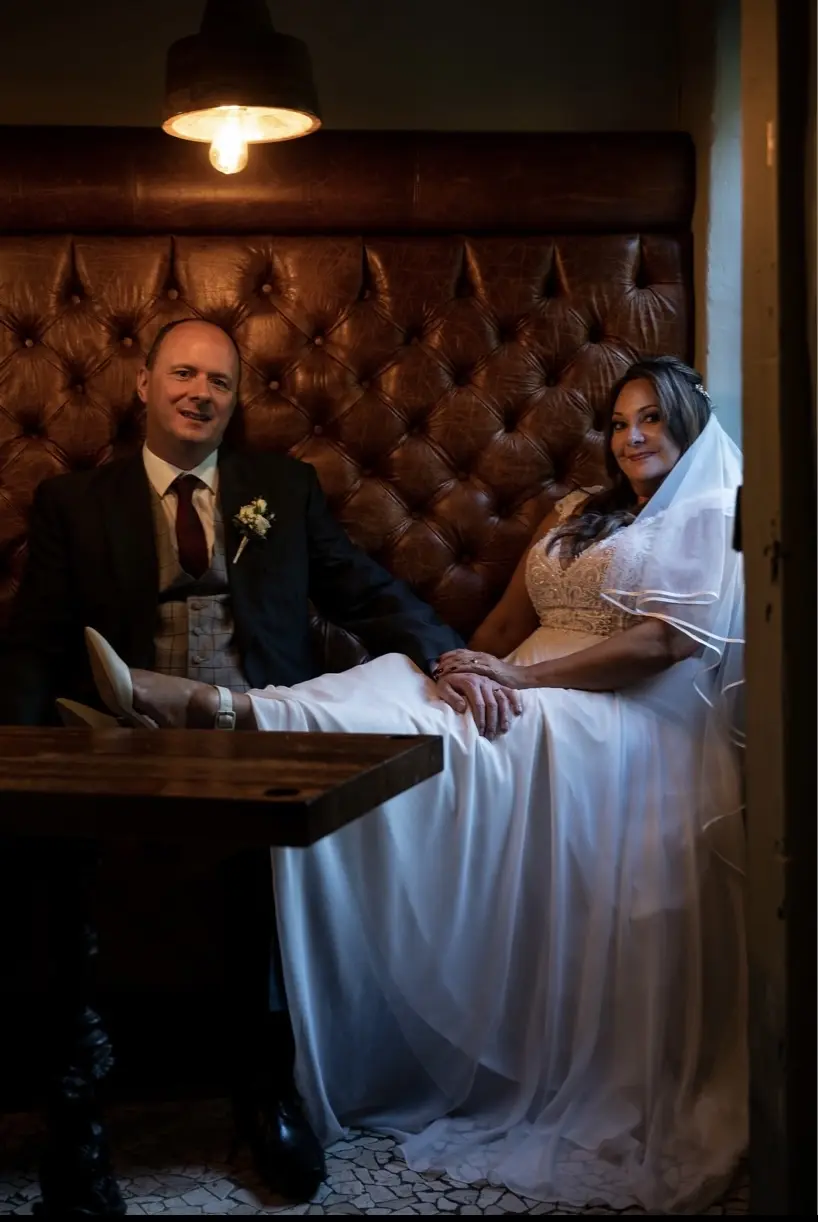 Bride Wearing Chiffon Lace Wedding Dress Called June By Maggie Sottero Sitting At A Booth With Groom