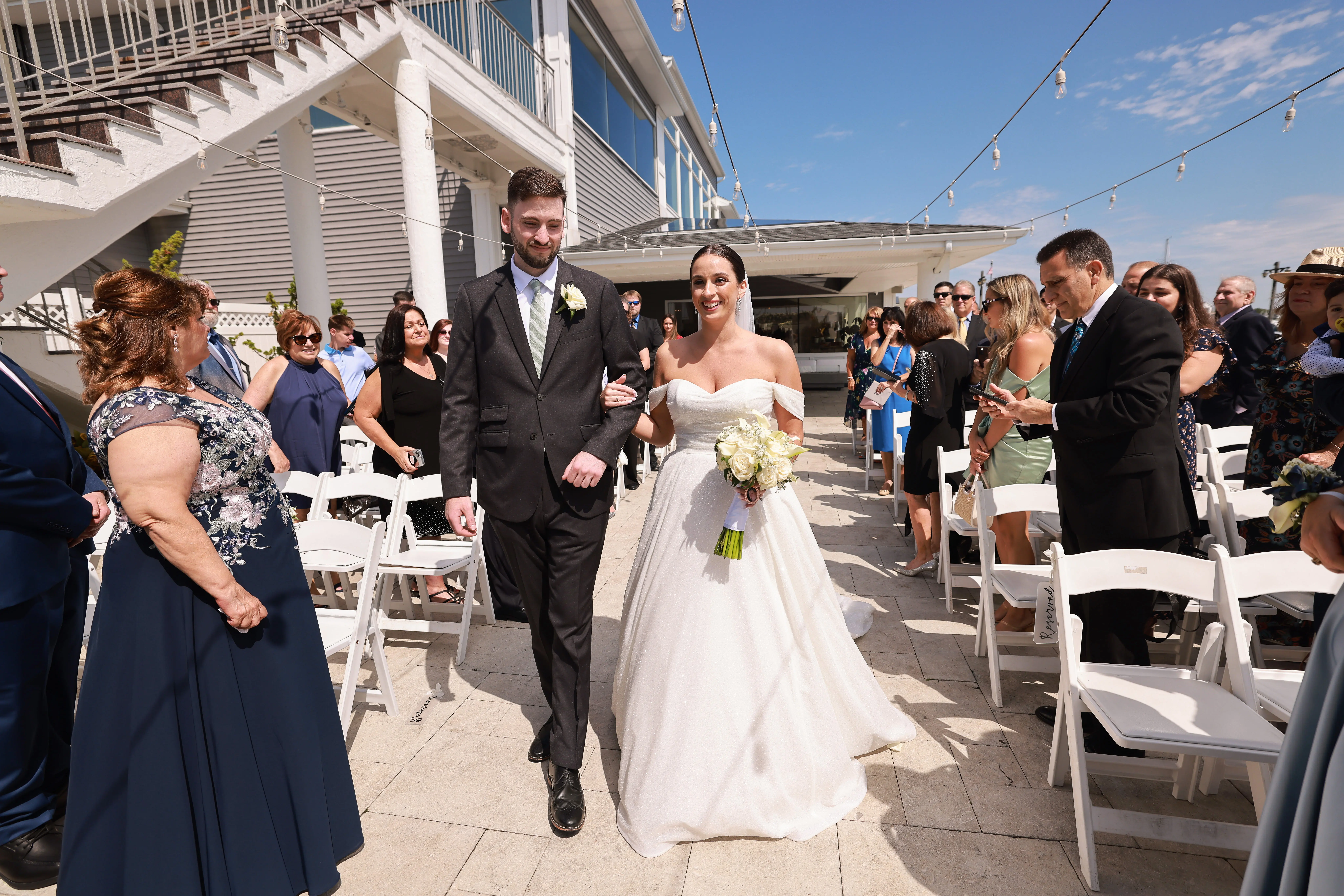 Bride wearing Anniston wedding dress by Sottero and Midgley walking down the aisle with her groom