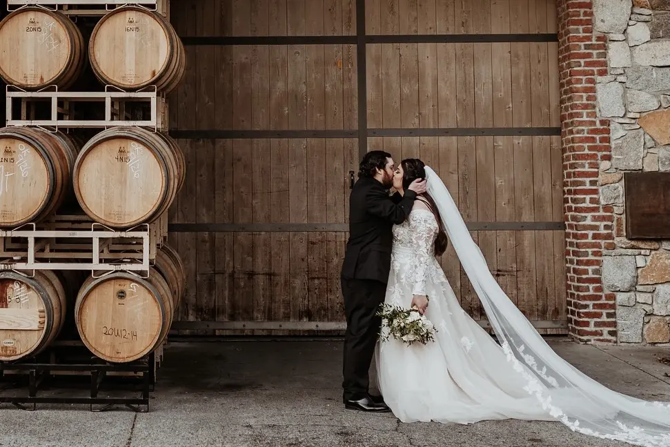 Bride Wearing Long Sleeve Lace Wedding Dress Called Raphael By Maggie Sottero Kissing The Groom
