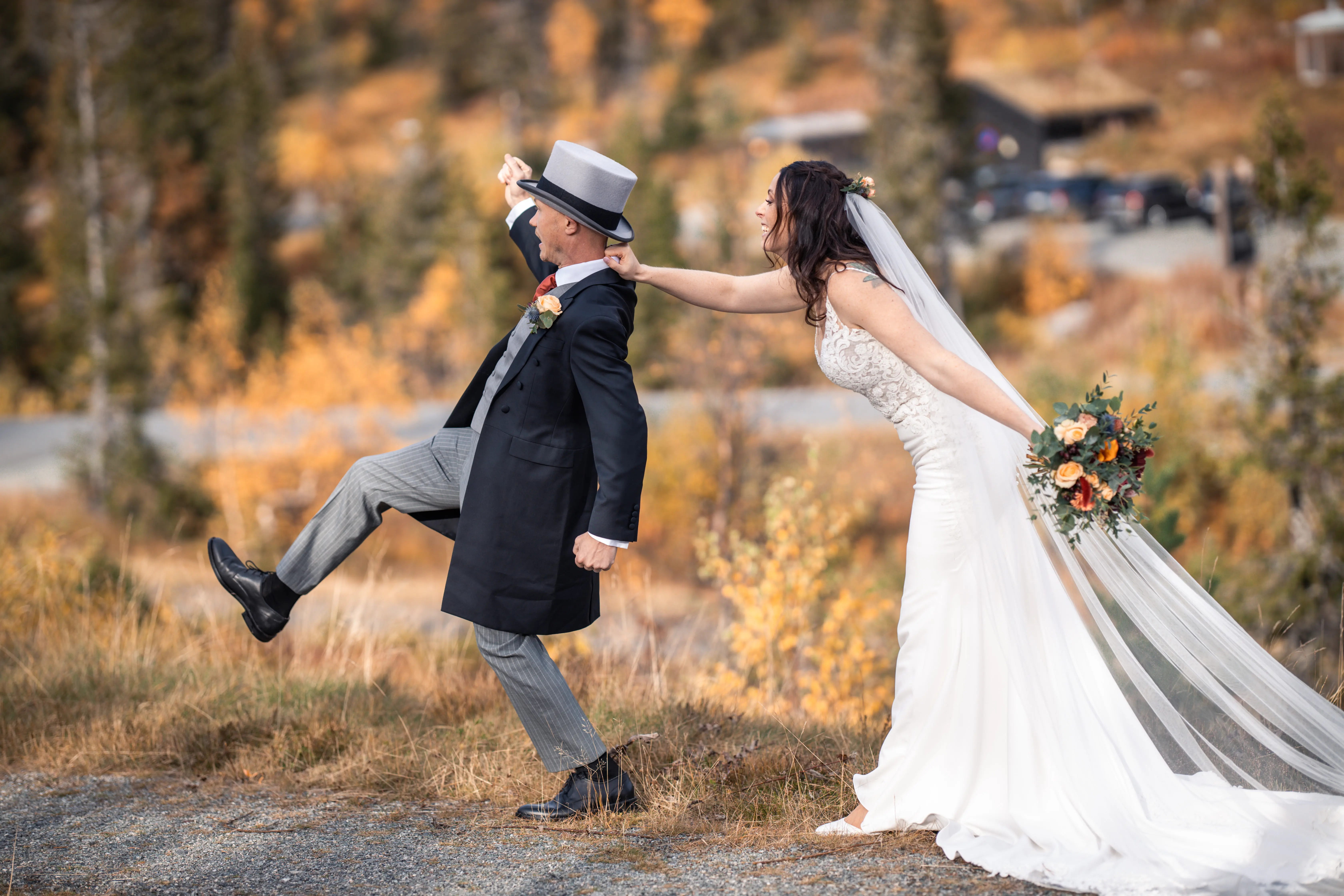 Bride and groom posing like he is trying to run away and the bride grabs his collar.