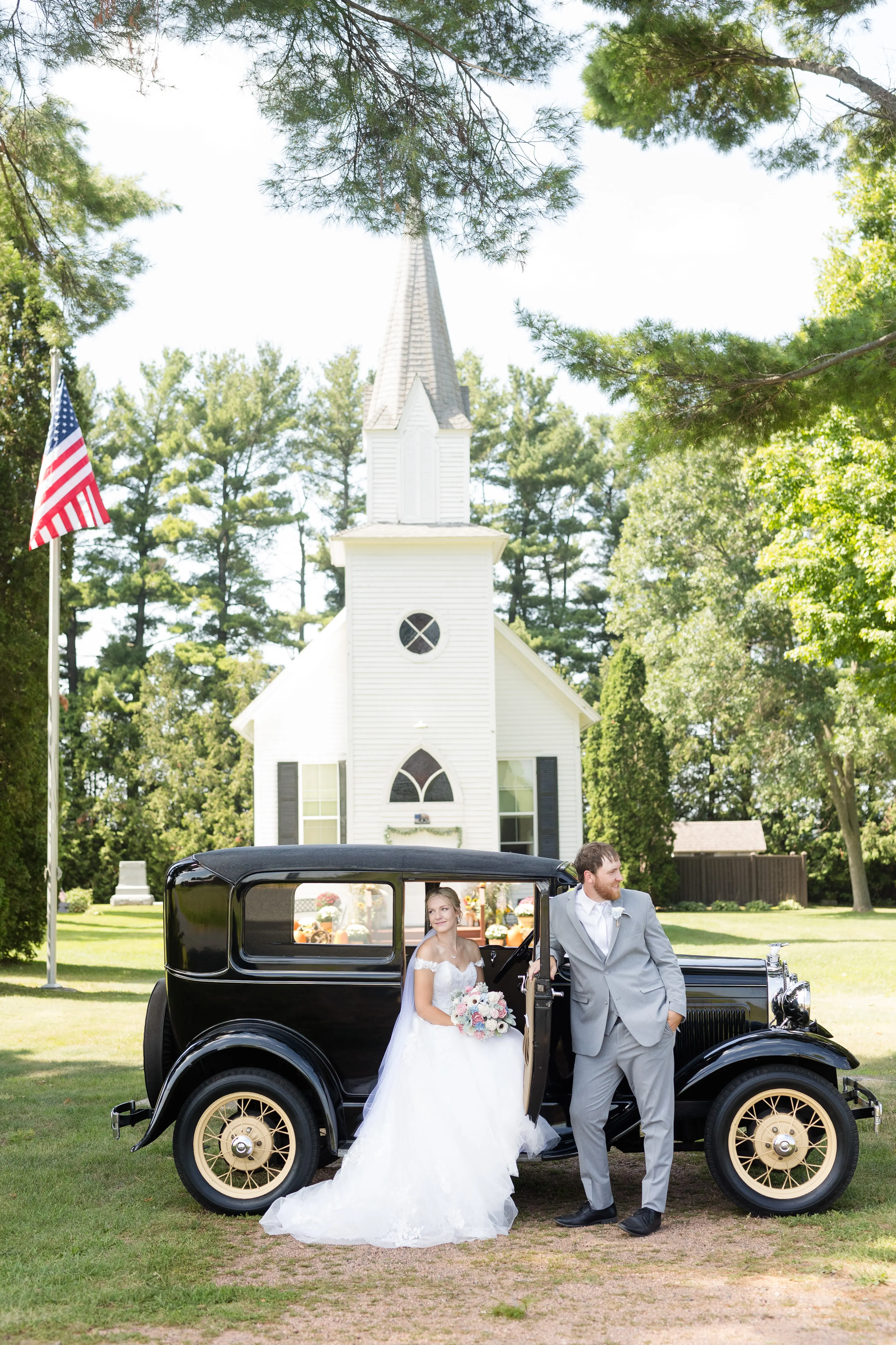 Bride Wearing Ballgown Wedding Dress Called Harlem By Maggie Sottero Sitting In Vintage Car With Groom