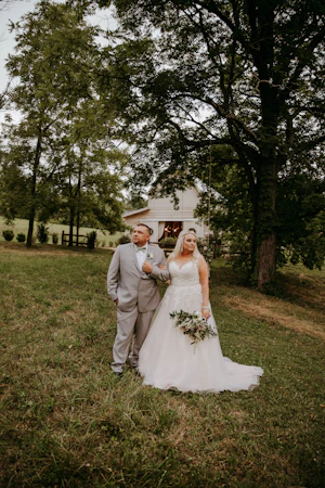 Groom and Bride at an Outdoor Wedding Wearing Lace Ballgown Wedding Dress Called Olivia by Rebecca Ingram