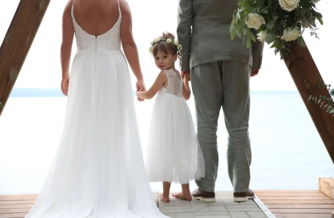Bride Wearing Simple Chiffon Wedding Dress Called Marta Lynette By Rebecca Ingram With Flower Girl Looking Back