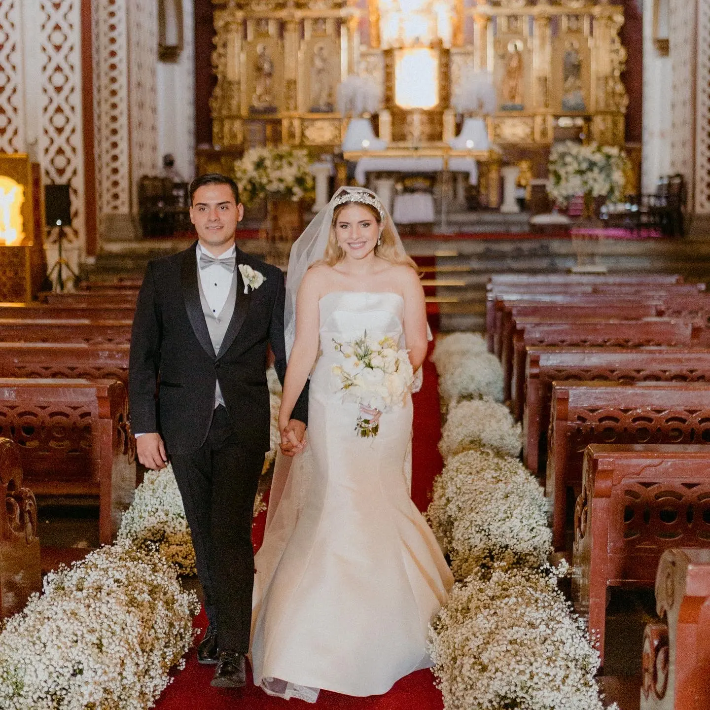 Bride Walking Down Aisle in a Church Holding Groom's Hand Wearing Bridal Dress Called Mitchell by Maggie Sottero