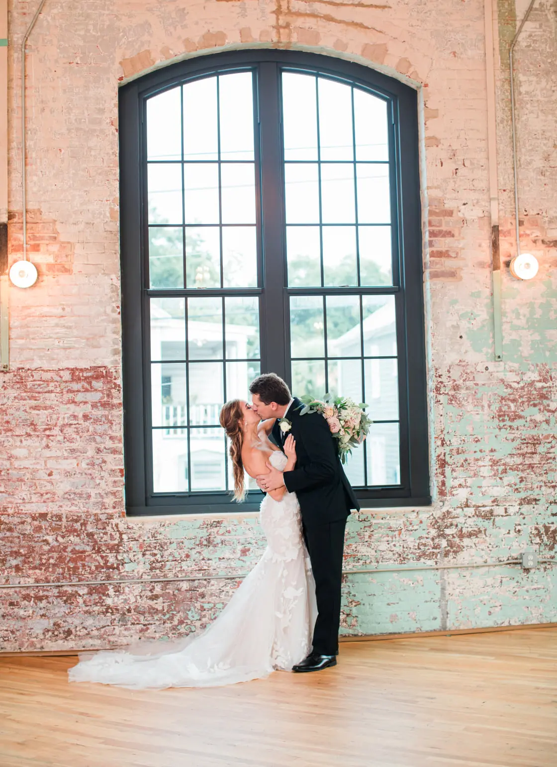 Bride with groom wearing strapless mermaid wedding dress with oversized lace