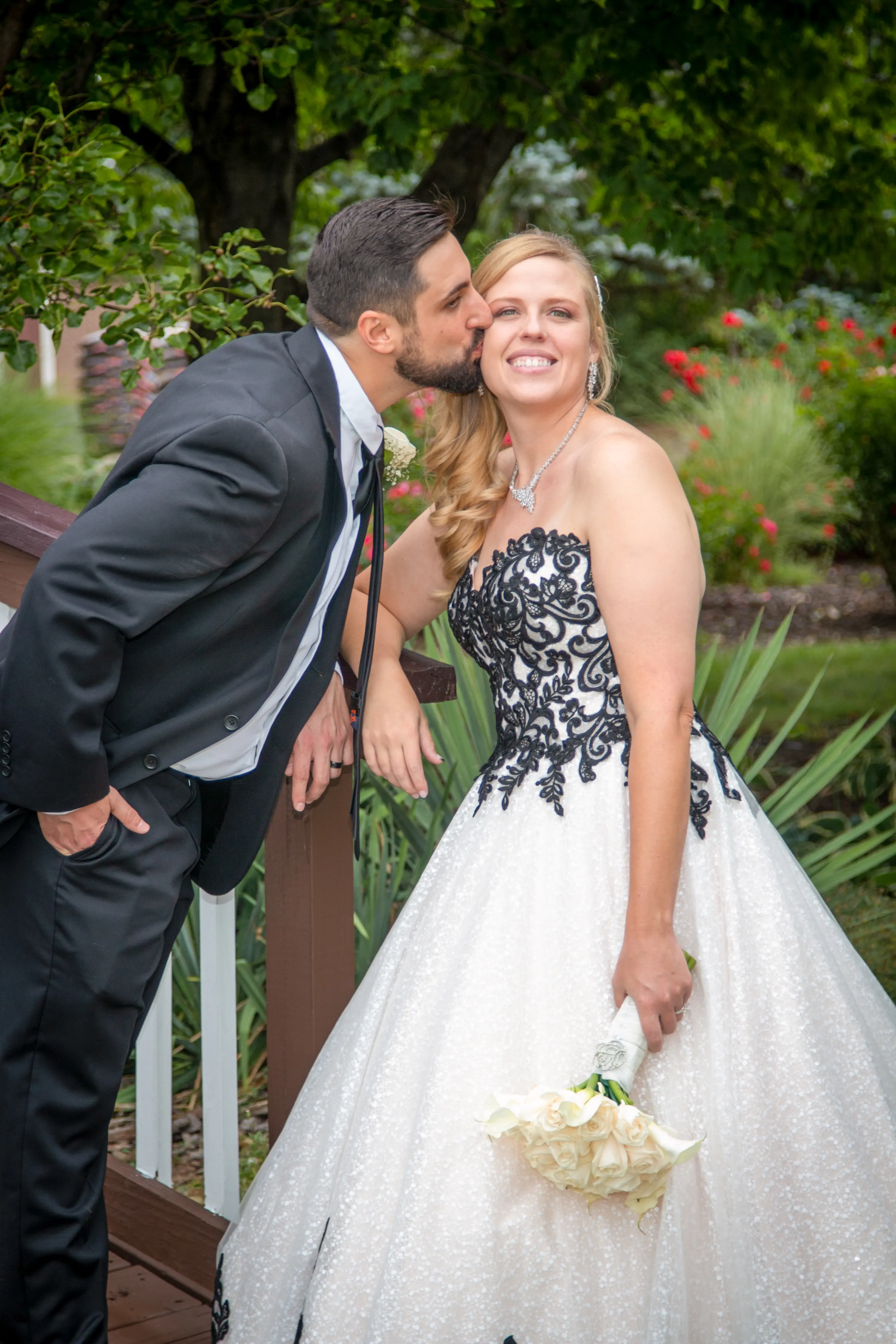 Bride Wearing A-Line Black Lace Wedding Dress Called Tristyn By Maggie Sottero And The Groom Kissing Her Cheek
