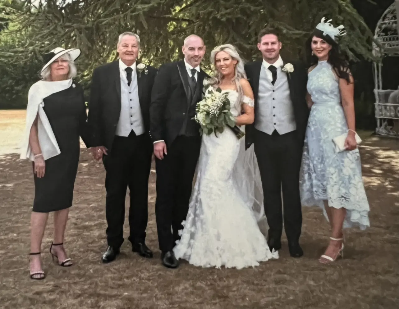 Bride Standing With Family Wearing Fit And Flare Lace Wedding Dress Called Ryker By Sottero And Midgley