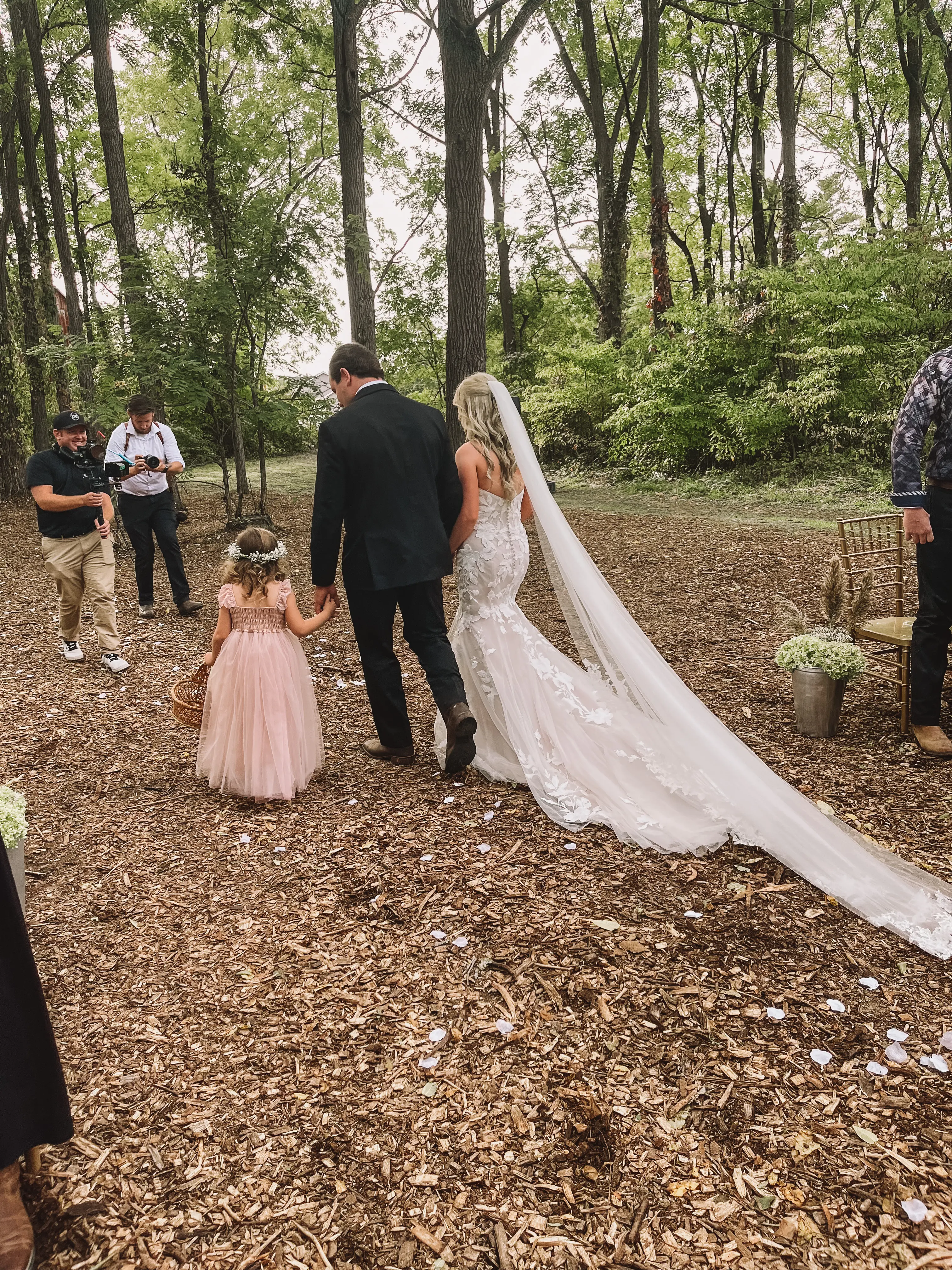 Bride in sparkle tulle train wedding dress called Hattie by Rebecca Ingram with groom and flower girl