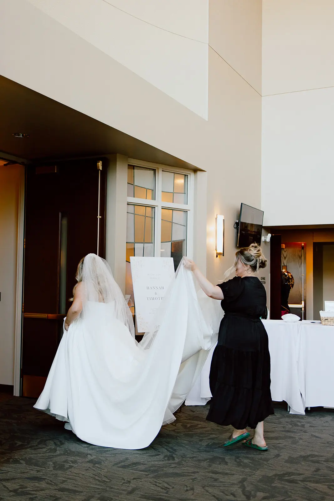Bride wearing Derrick by Maggie Sottero holding up her train and walking into her ceremony