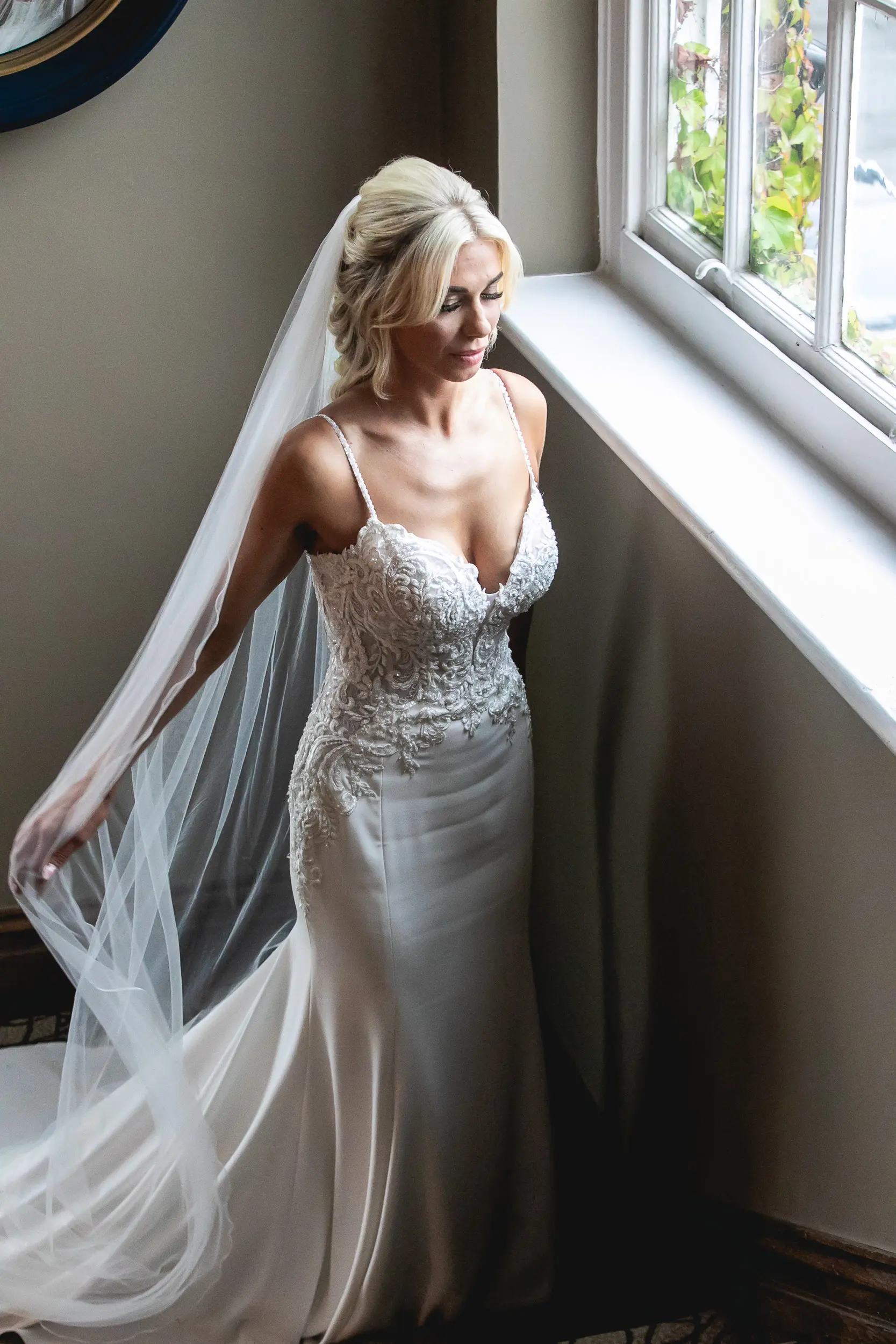 Bride stood by window wearing wedding dress called Juanita.