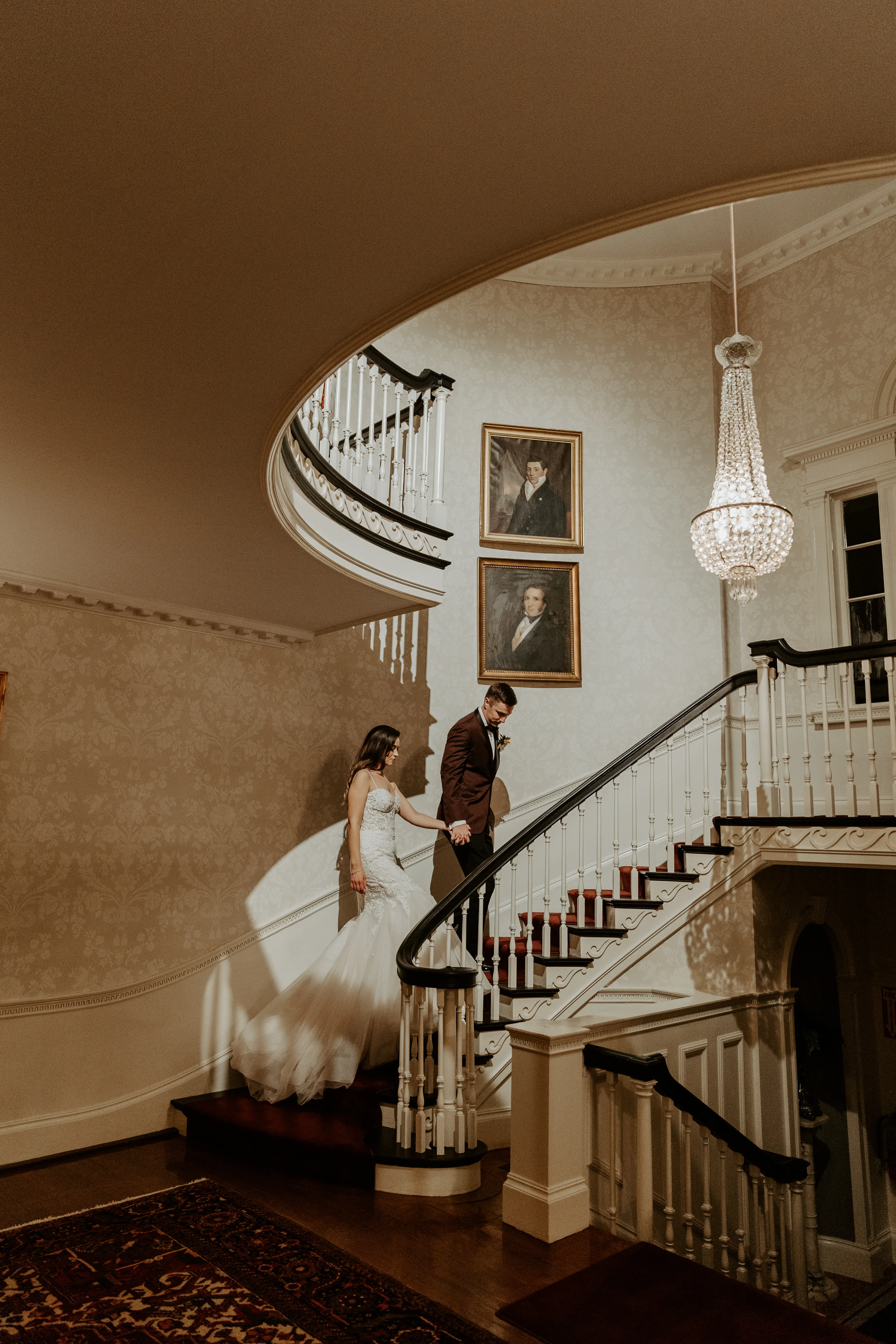 Bride with groom wearing lace fit-and-flare wedding dress holding hands walking up staircase.