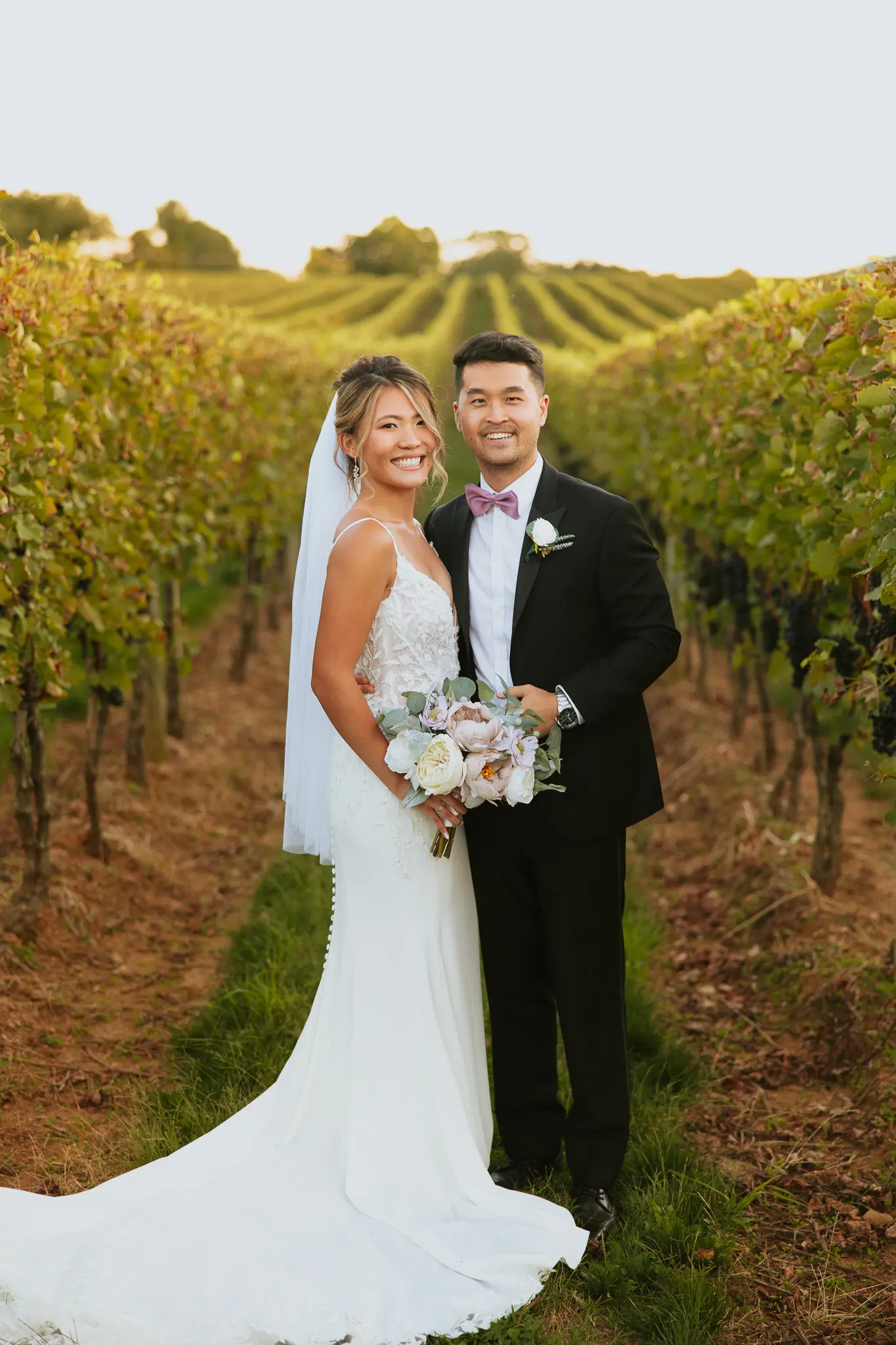 Bride In Lace Crepe Wedding Dress Called Alda By Rebecca Ingram With Groom In Vineyard