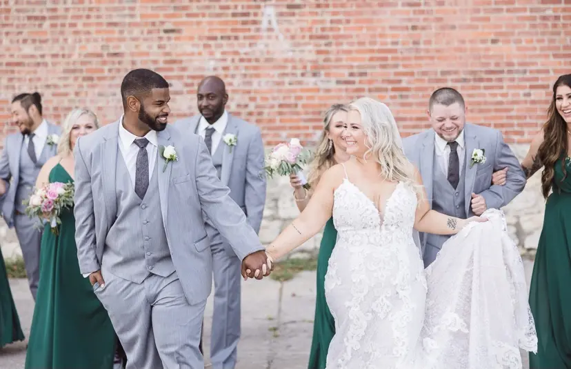 Newlyweds holding hands and smiling at each other.