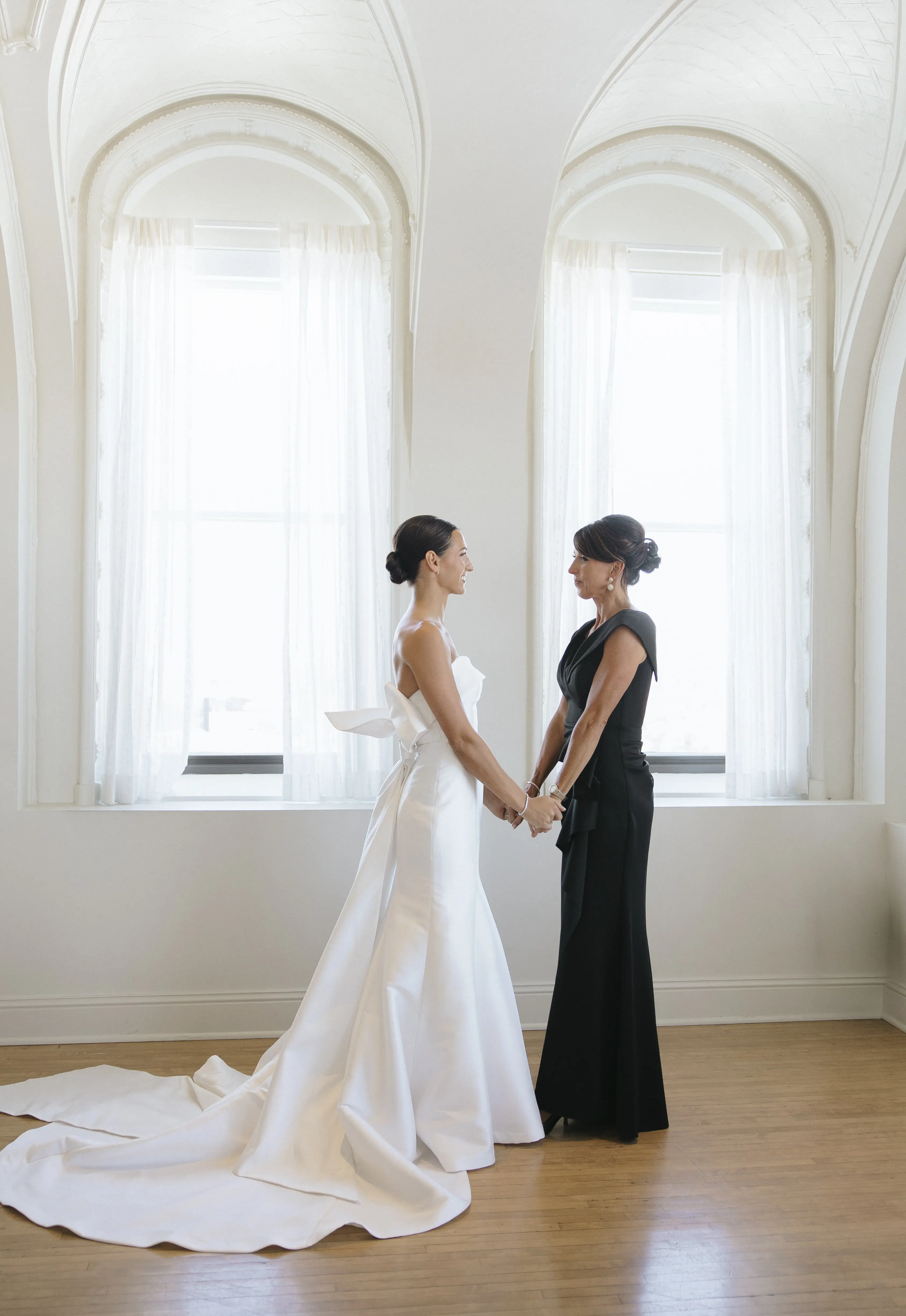 Bride wearing Mitchell wedding dress by Maggie Sottero holding hands with her mom