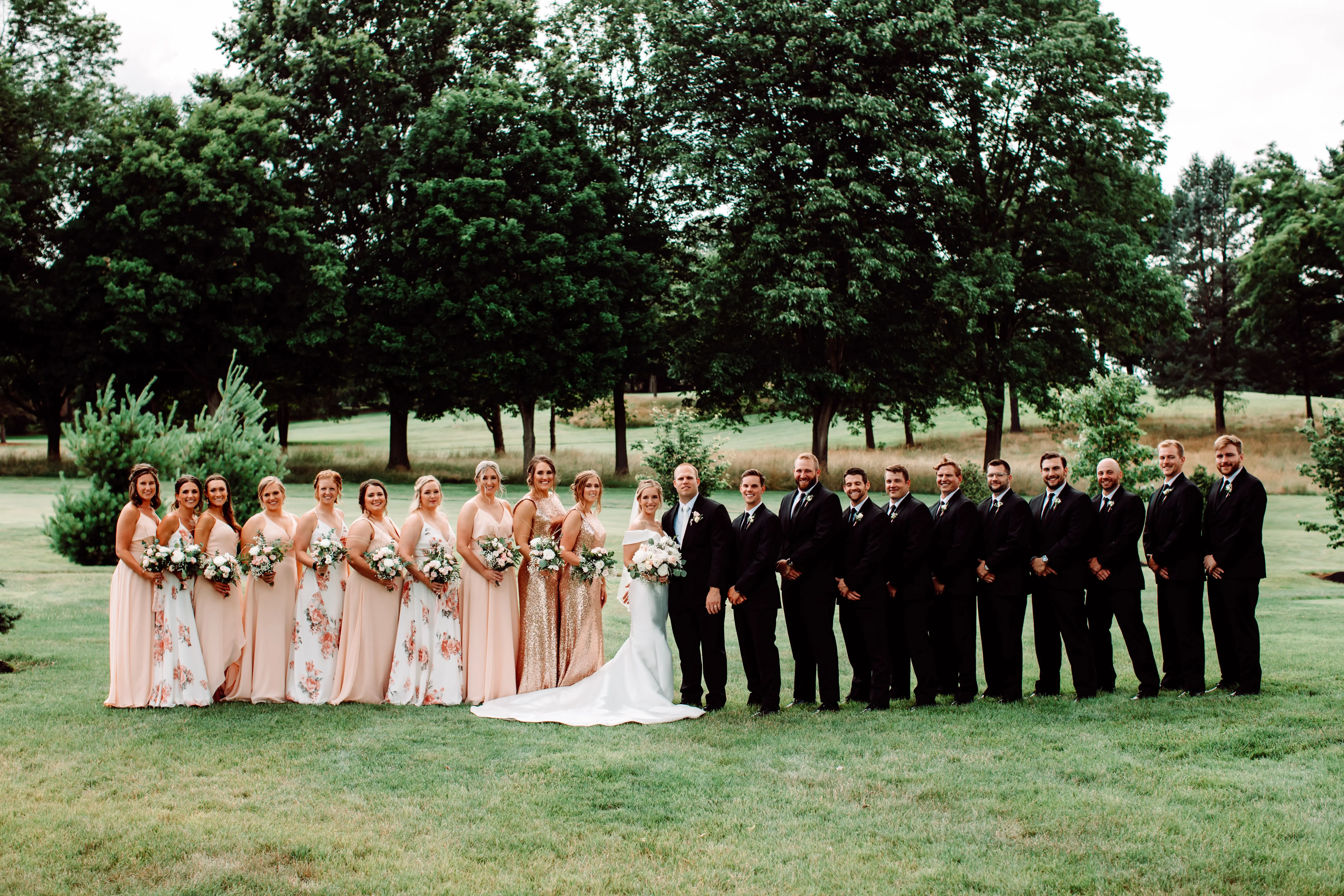 Full wedding party gathered together all looking at the camera.