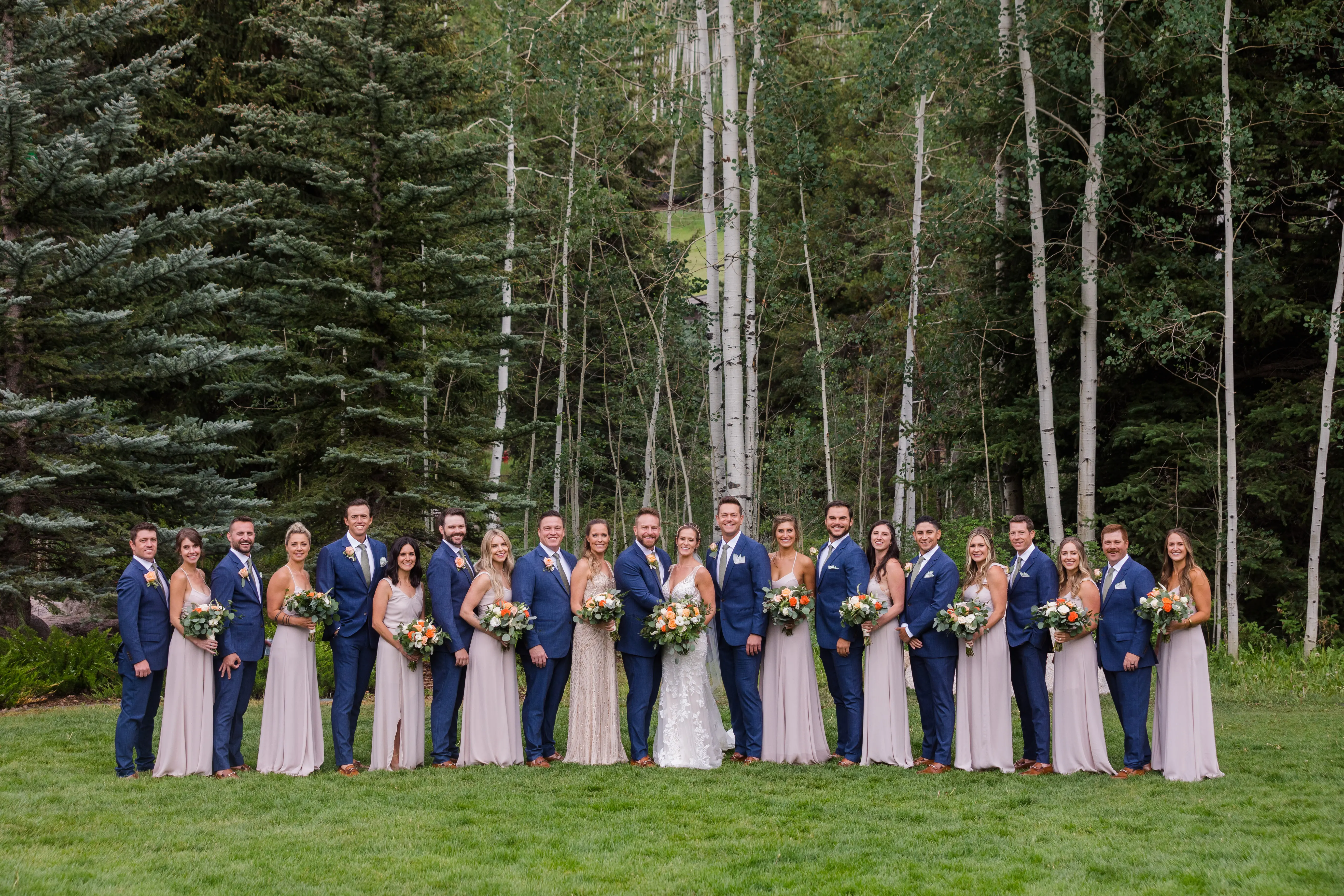 The wedding party wearing colors of an orange, navy blue and taupe theme.