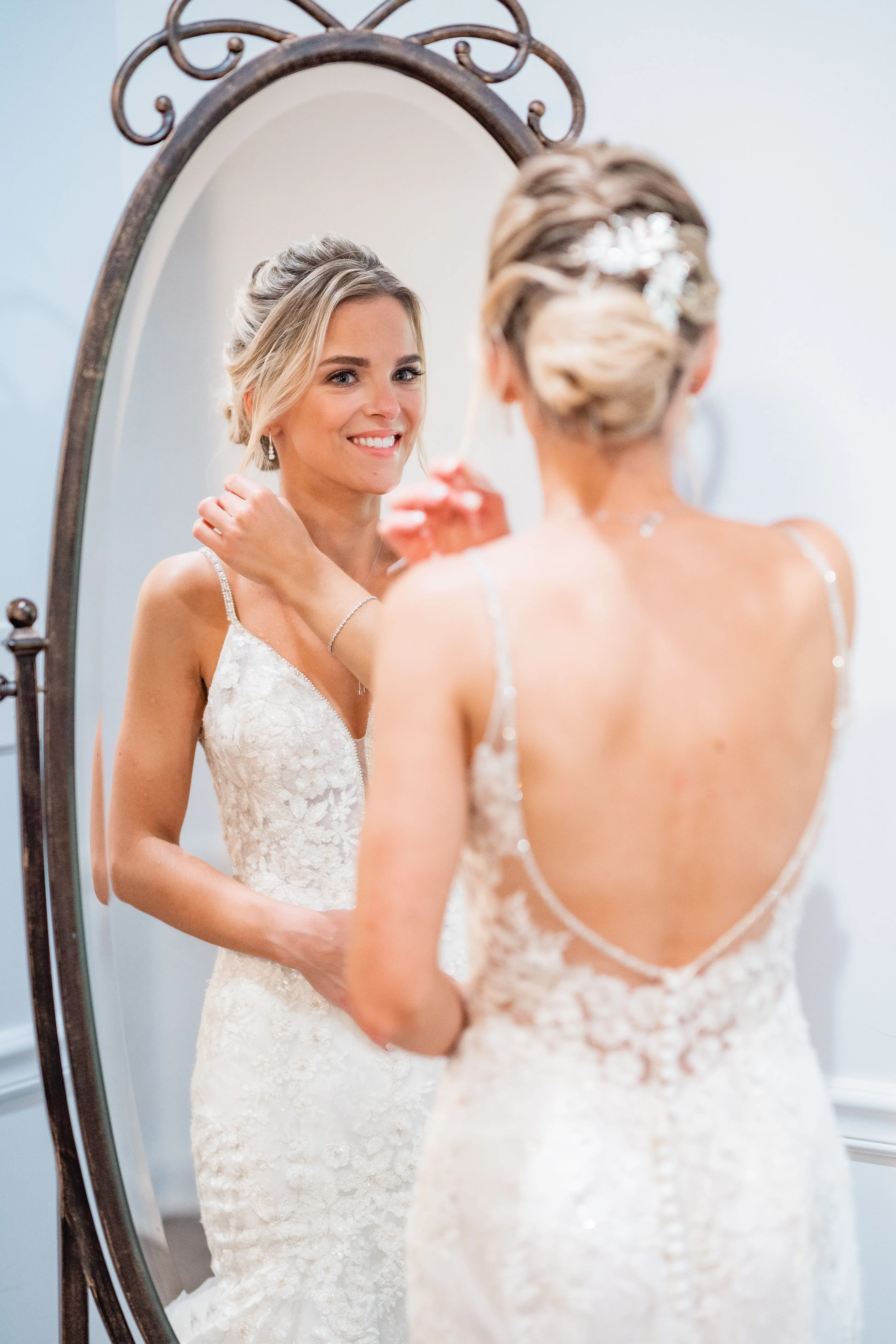 Bride touching hair looking in mirror before wedding wearing wedding dress called Inga.