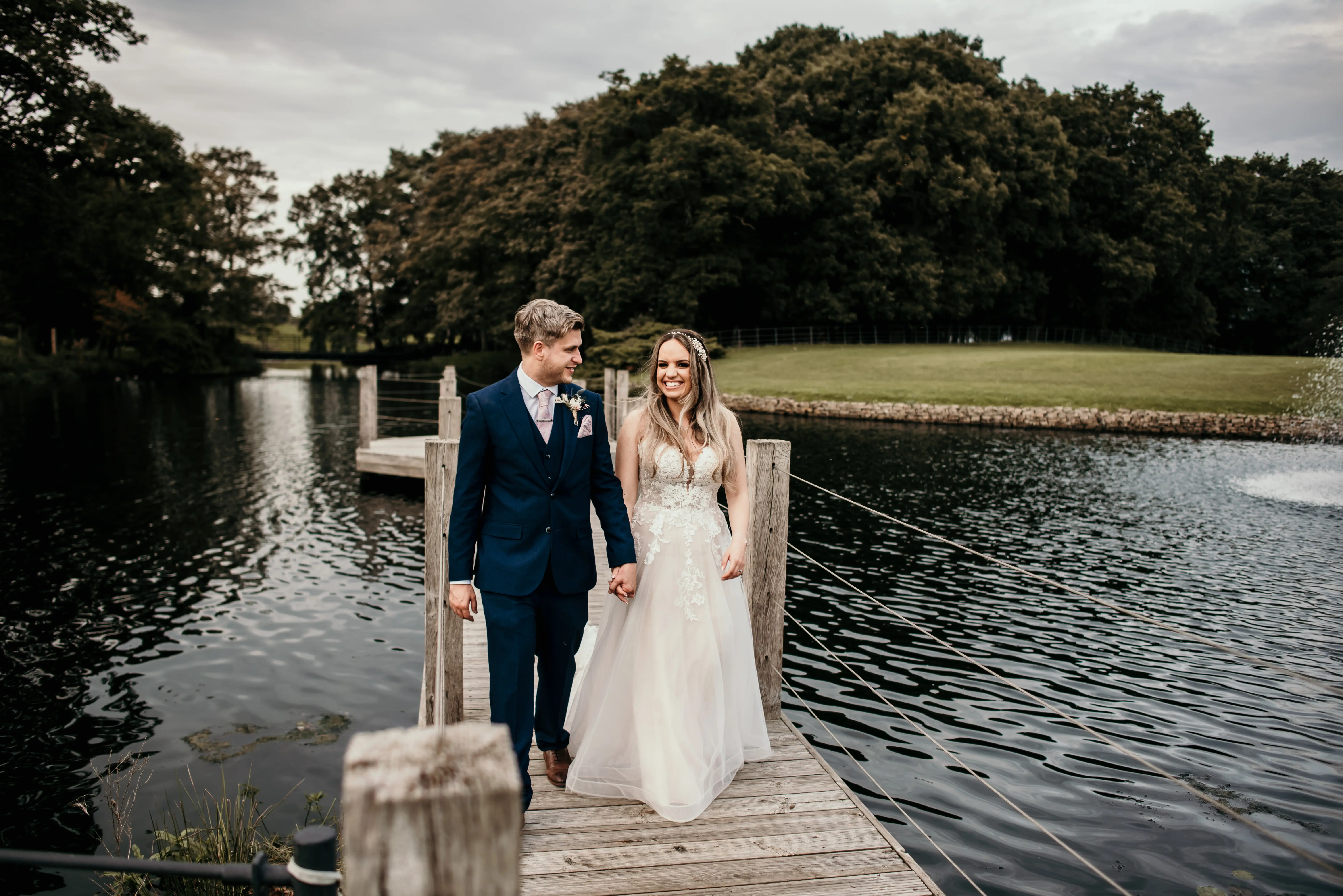Bride wearing Stevie wedding gown by Maggie Sottero holding hands with her husband