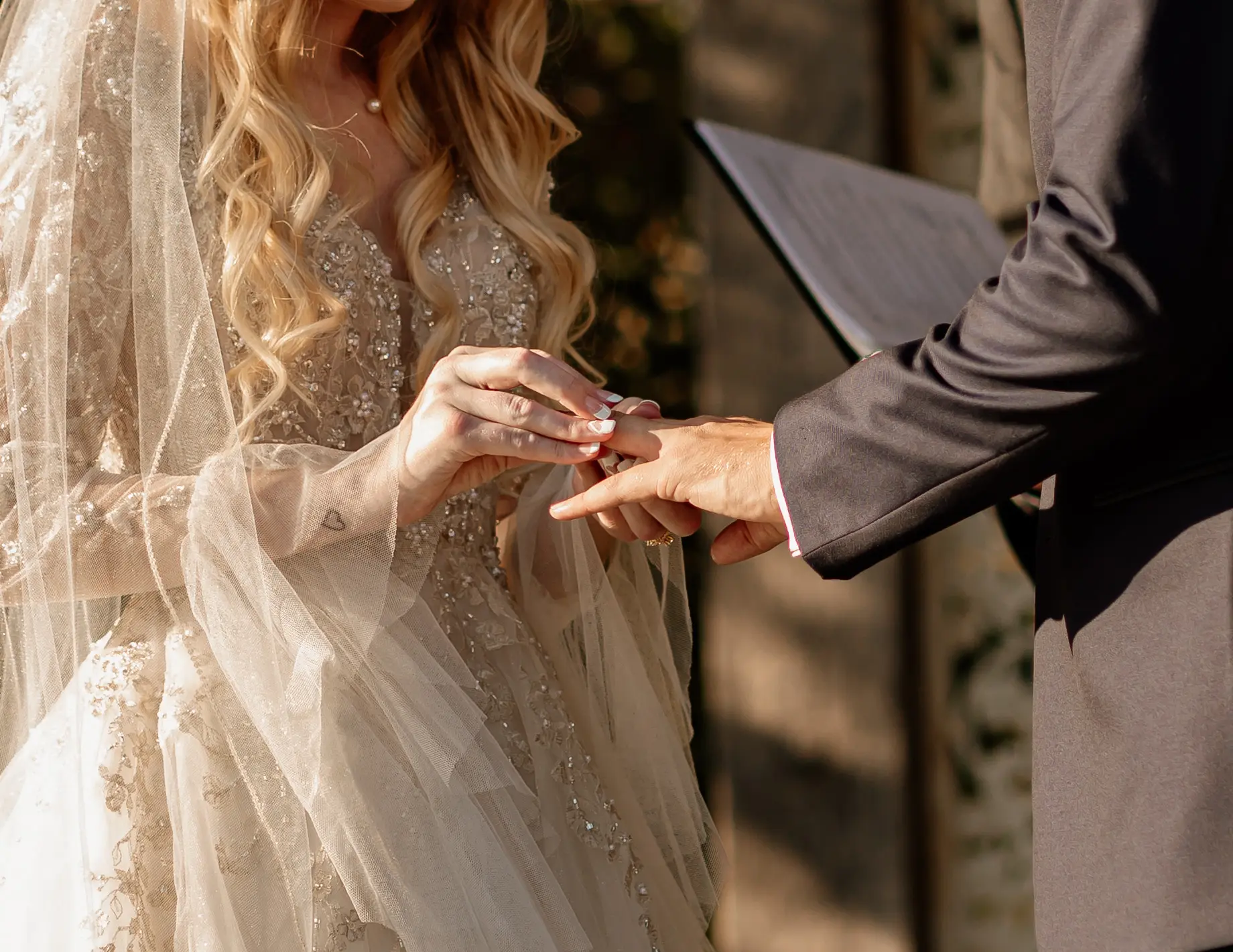 Bride putting ring on her husband's ring finger.