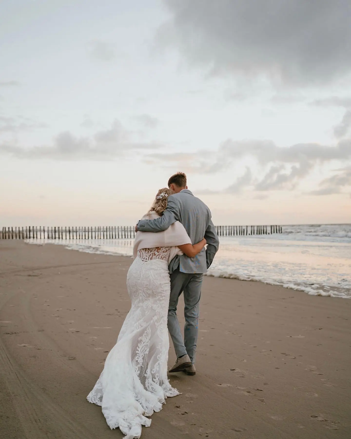 Bride Wearing Illusion Lace Back Wedding Dress Called Hamilton By Sottero And Midgley Hugging Groom Near The Ocean