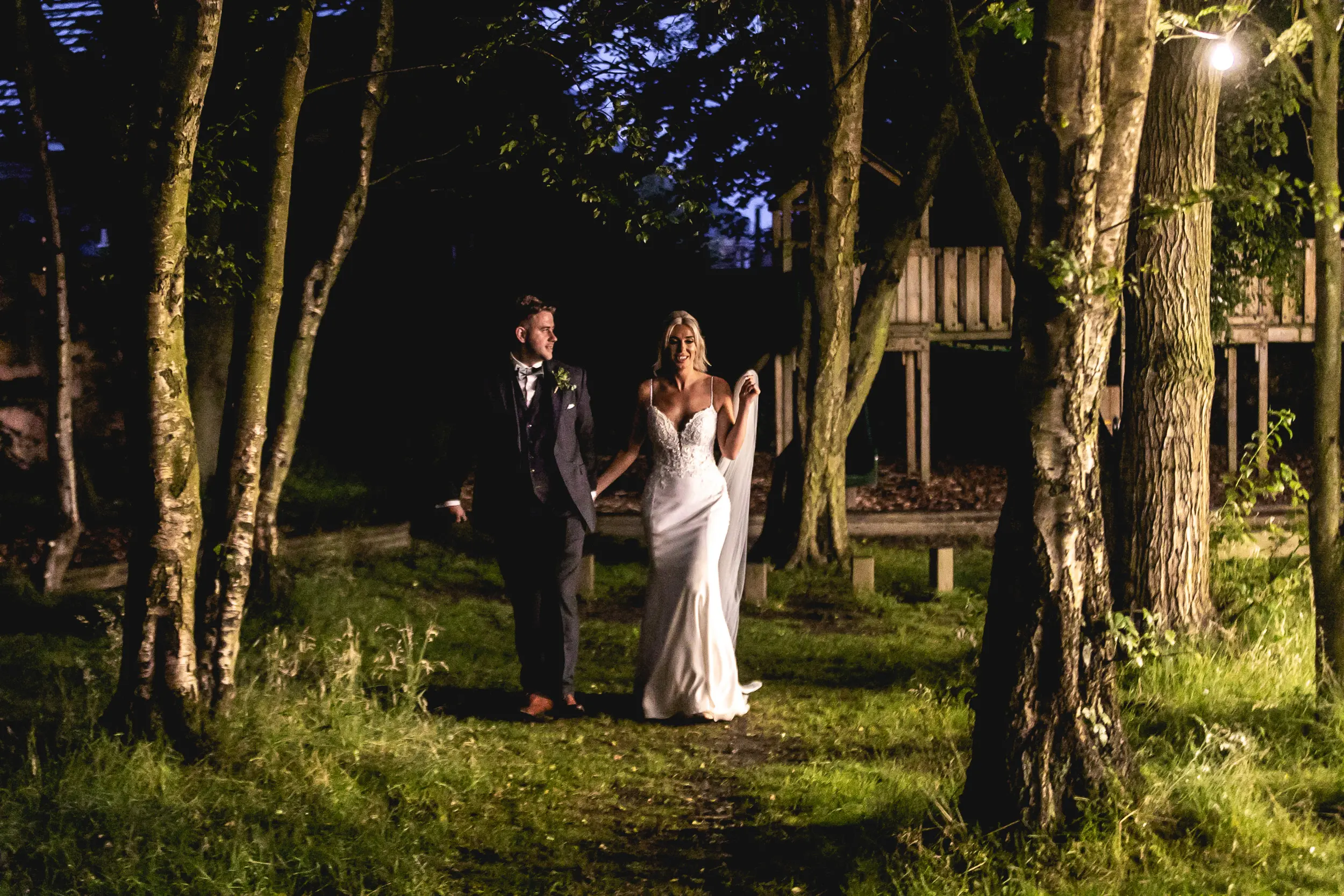 Bride and groom walking in the woods at sunset.