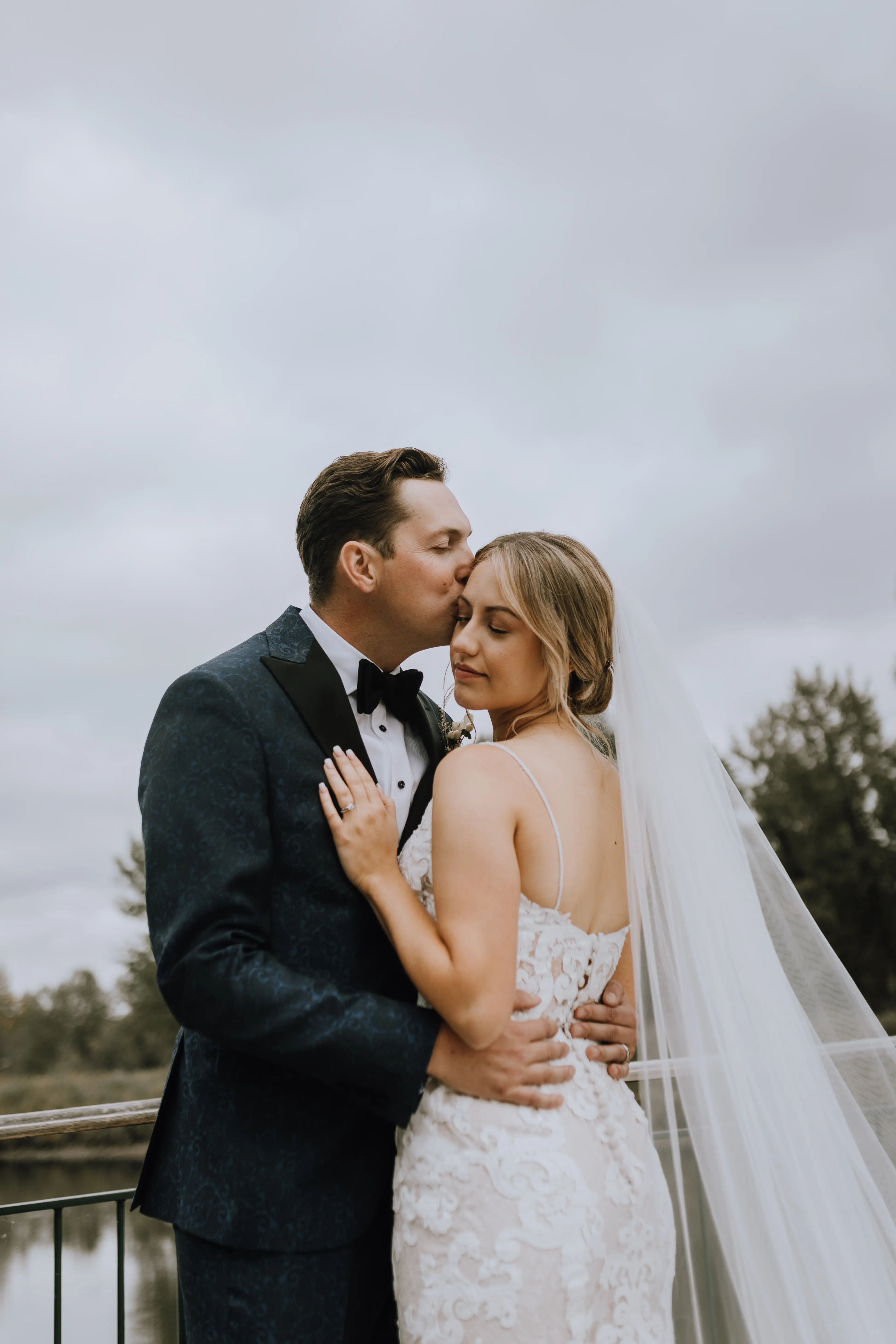 Bride with groom wearing a romantic lace sheath wedding dress.